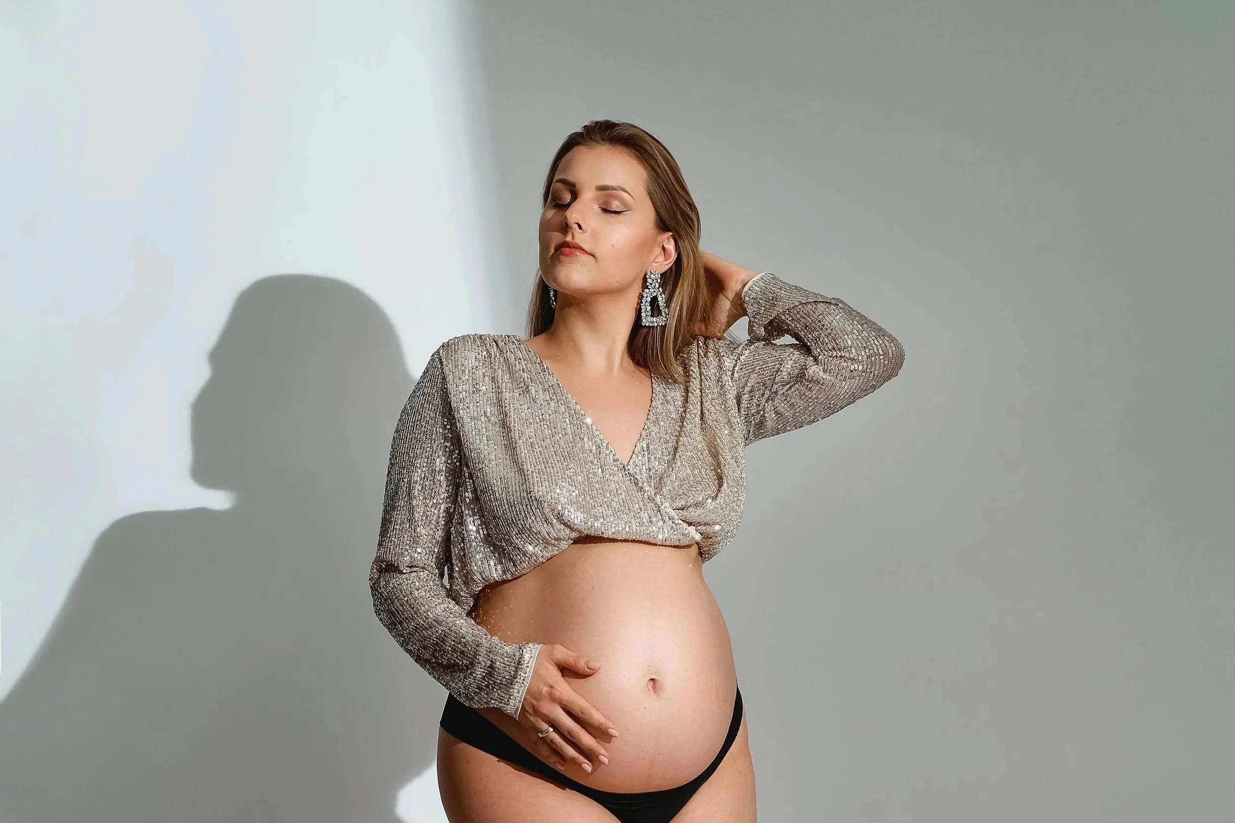 Artystyczna sesja ciążowa kobiety w ciąży eksponującej brzuszek – kobieca fotografia ciążowa Garwolin Mazowieckie