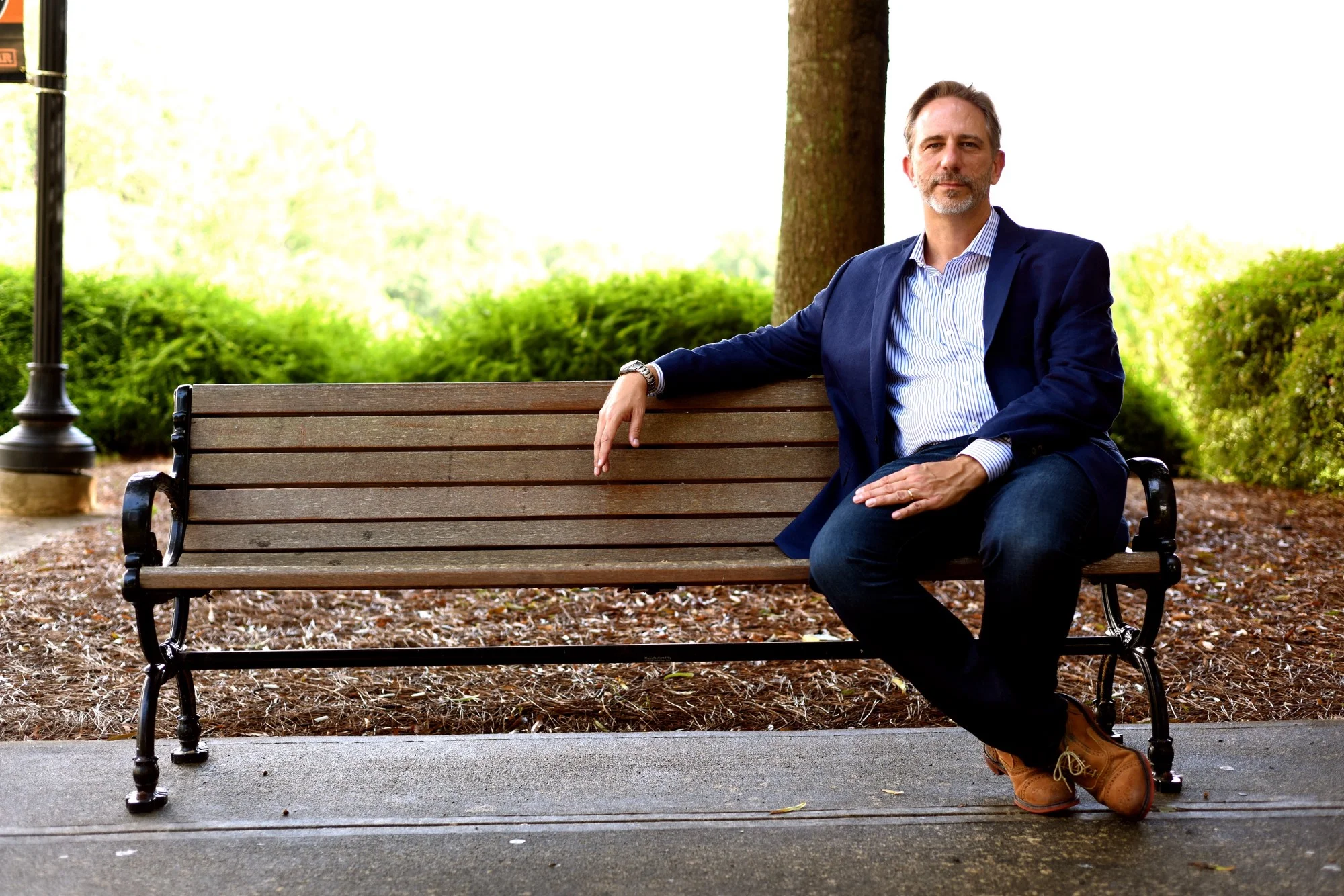 A photo of Dr. Gushee sitting in the far right side of a bench in a casual suit.