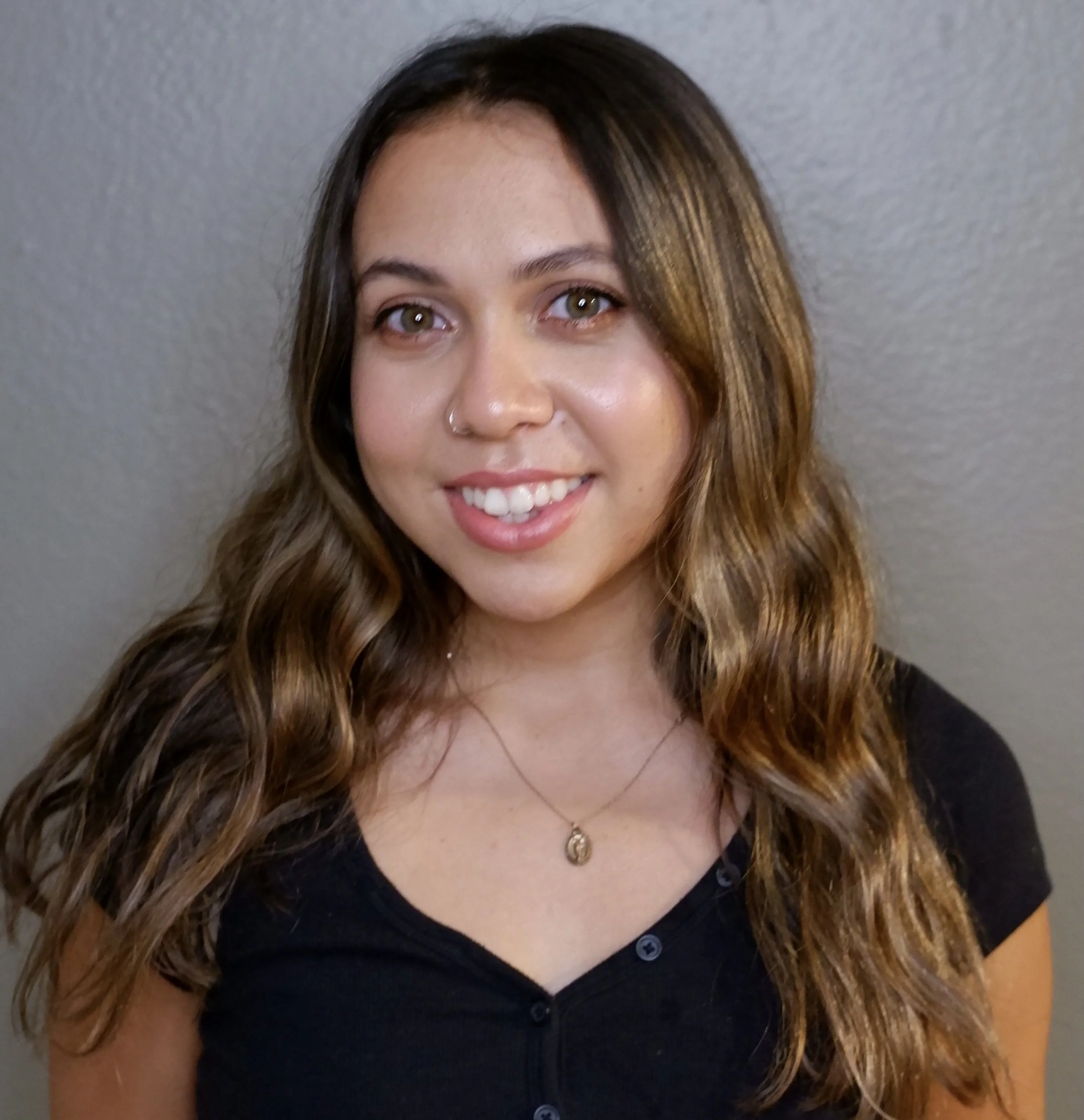 A photo of Hannah smiling in front of a wall.