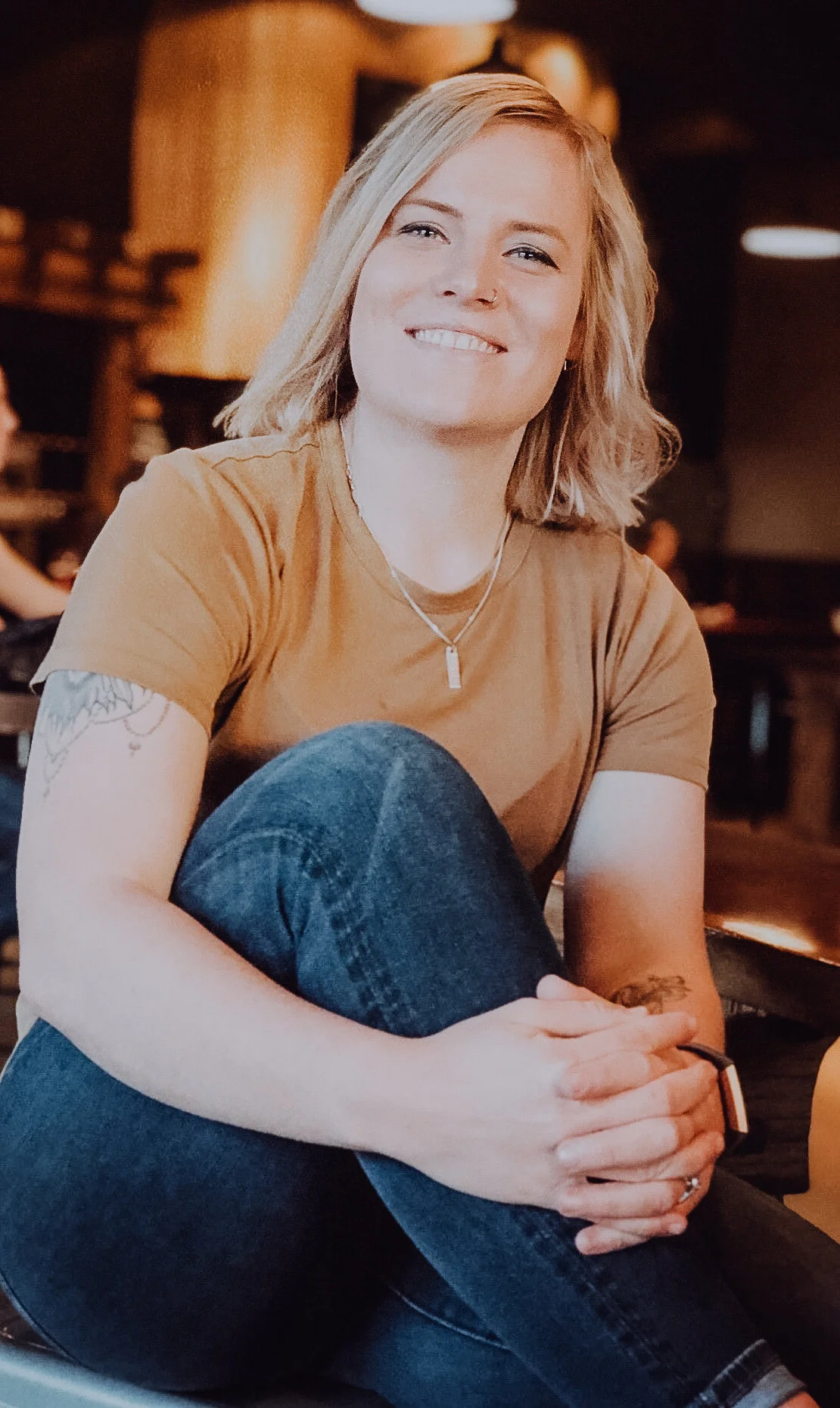 A photo of Alex with their knee in between their clasped hands.