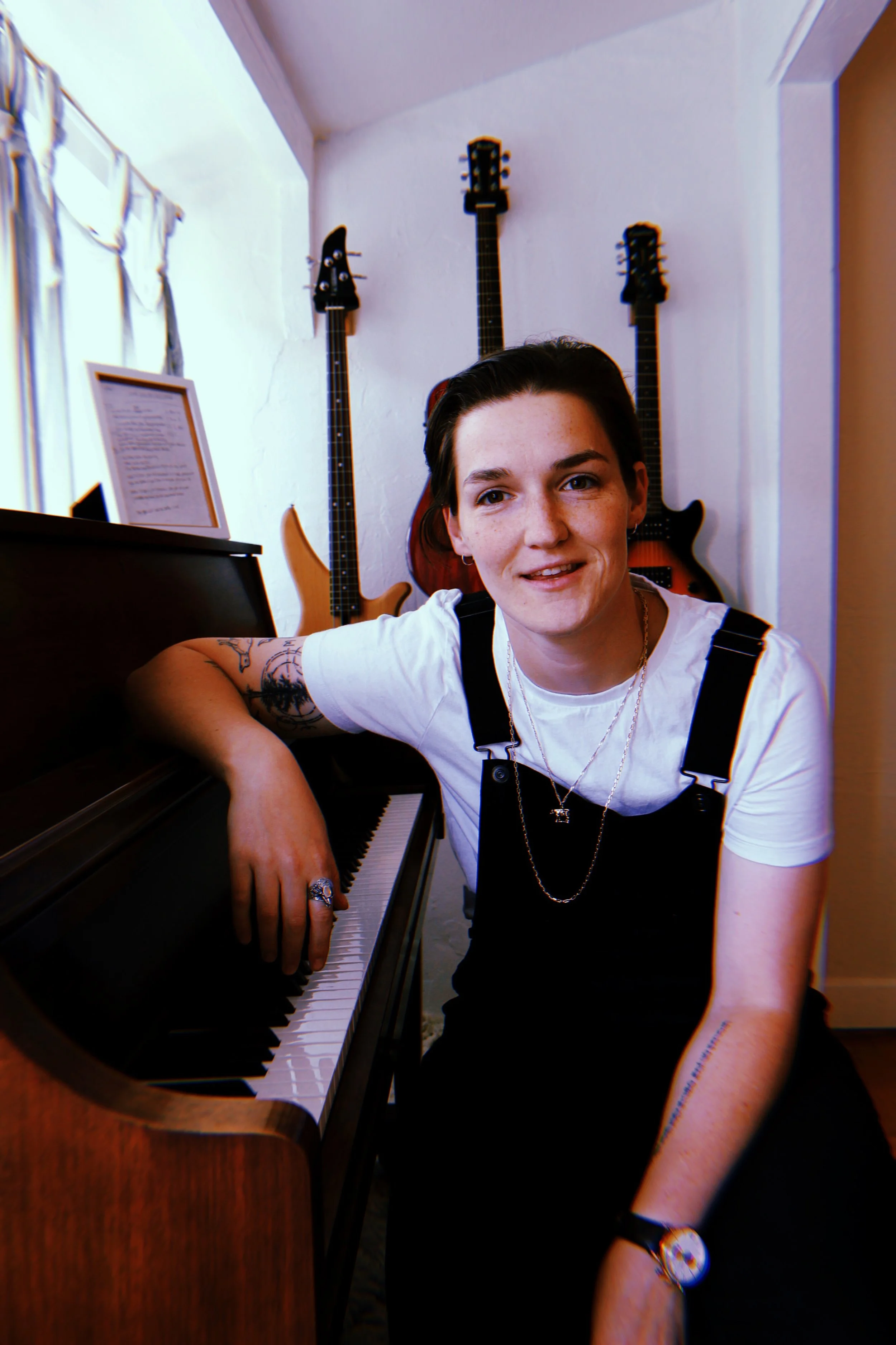 A photo of Grace in overalls leaning against her open piano.