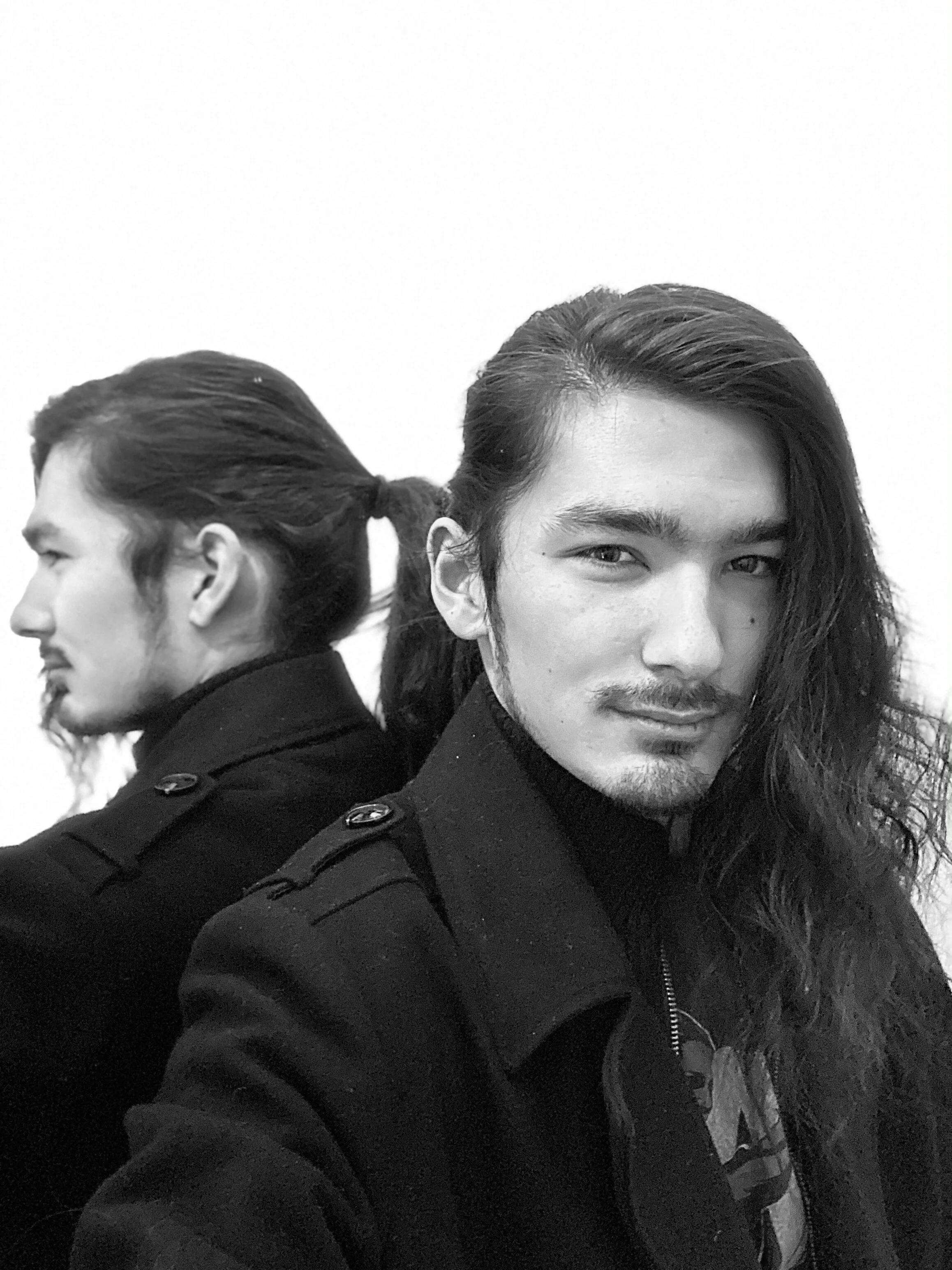 A photo of Joshua in greyscale leaning against a mirror with his back reflected.