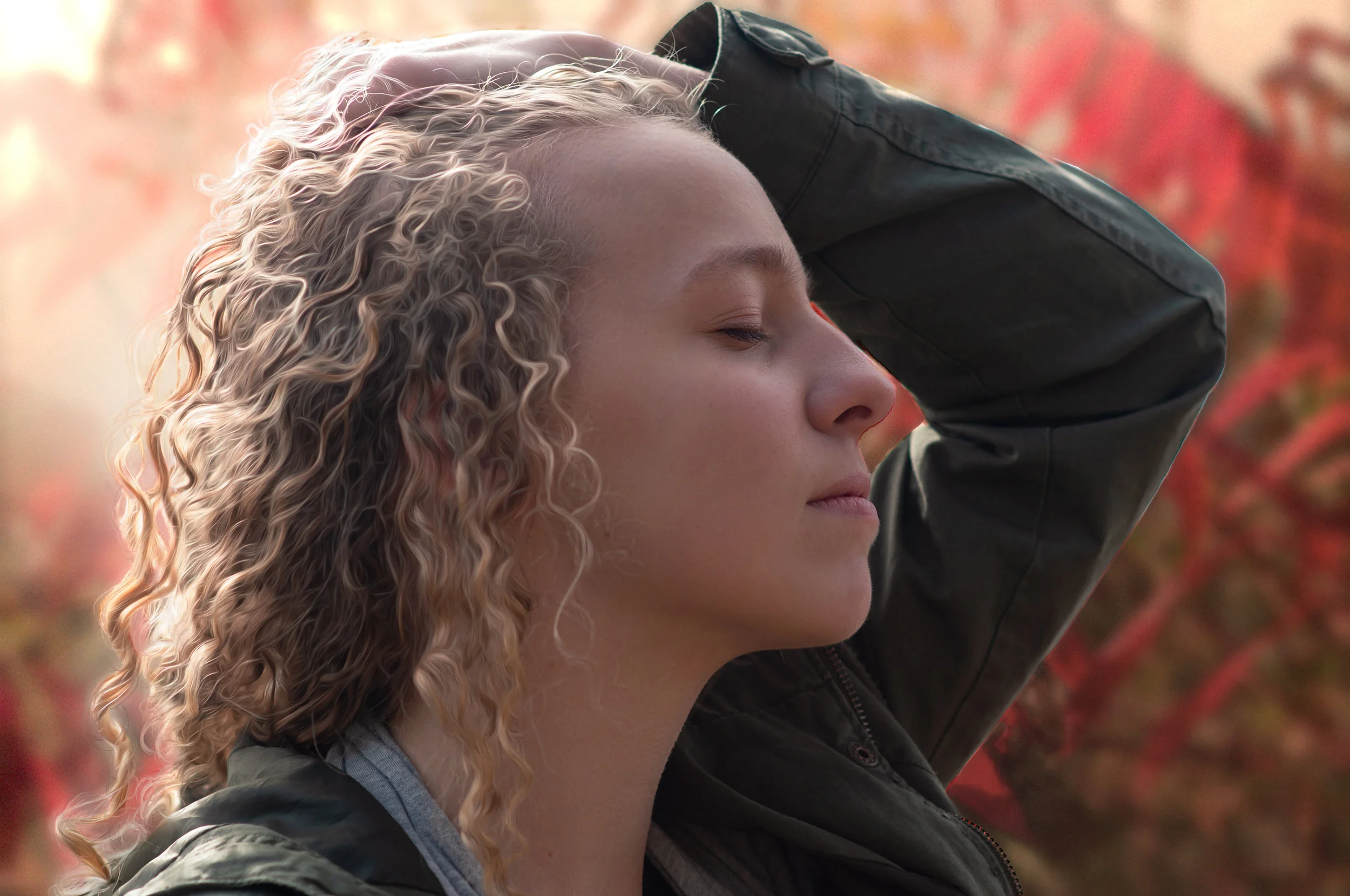 A side-profile photo of Leah with a hand on her head pulling her hair back.
