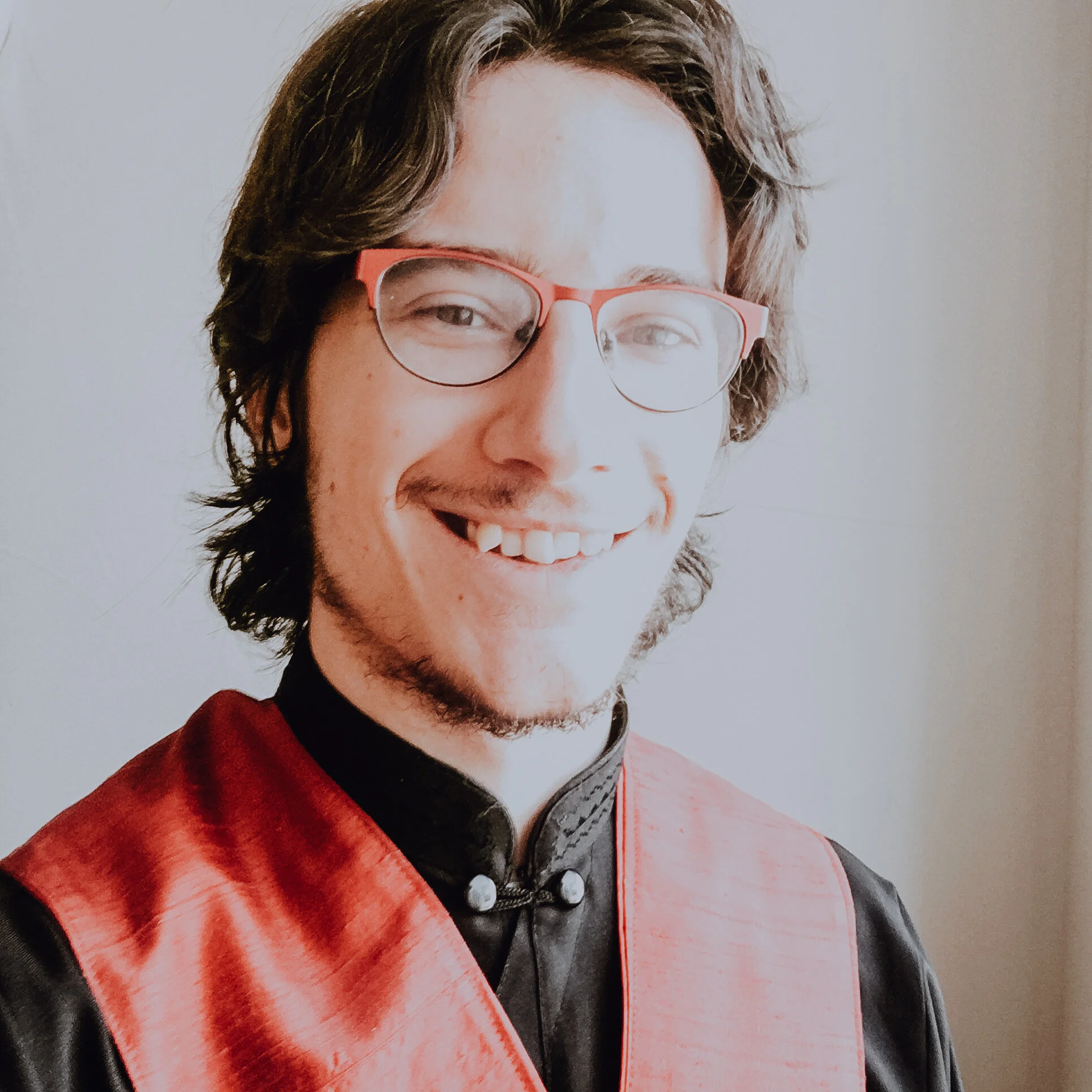 A photo of Micah smiling into the camera in front of a blank wall.