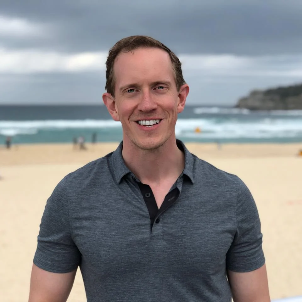 A photo of Otto on a beach wearing a grey polo.