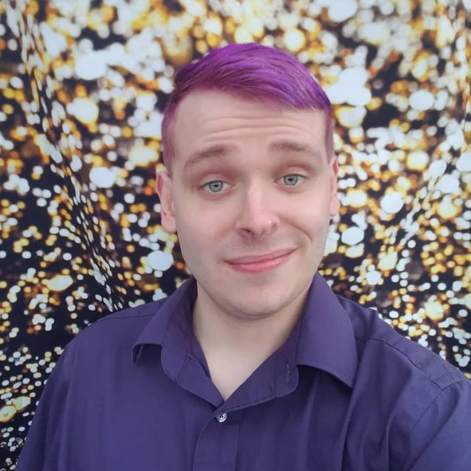 A photo of Phillip with purple hair in a purple shirt against a textured white and yellow background.