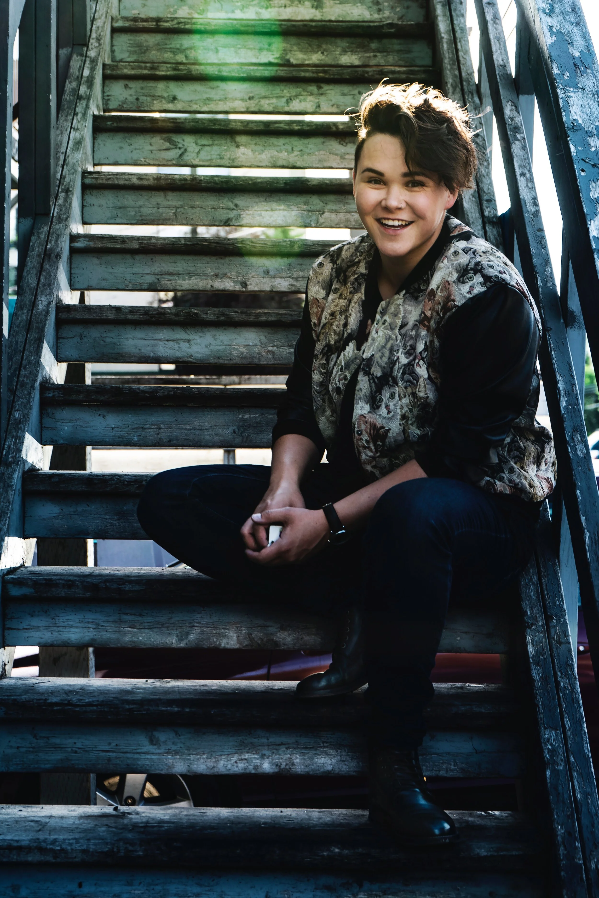 A photo of Renee smiling while sitting on an ascending staircase.