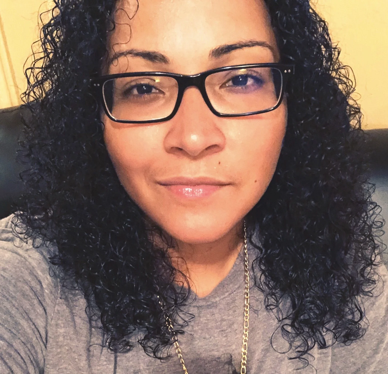 A selfie by Steph, wearing a grey t-shirt and a gold necklace.