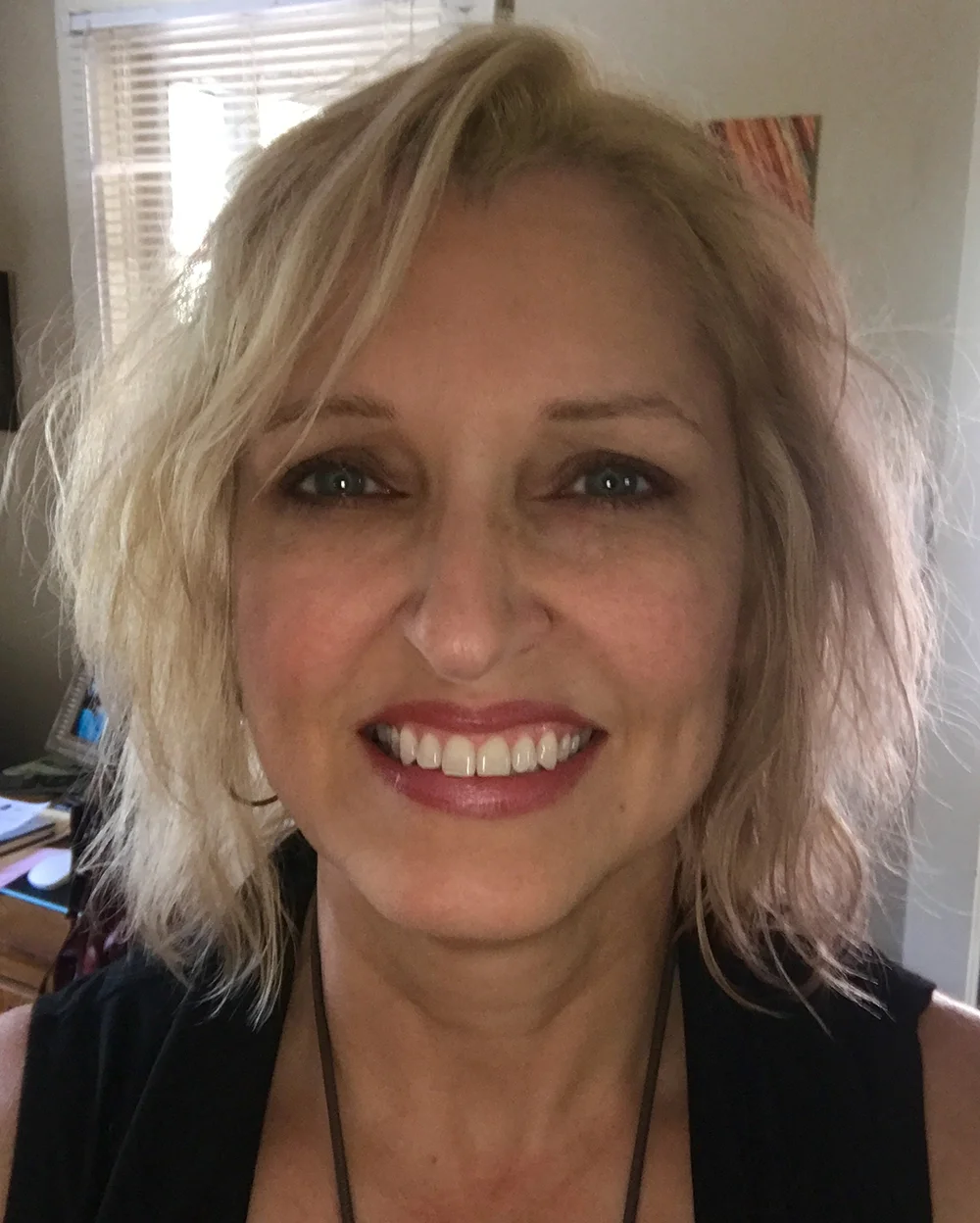 A photo of Tamra in selfie form wearing a black shirt and necklace.