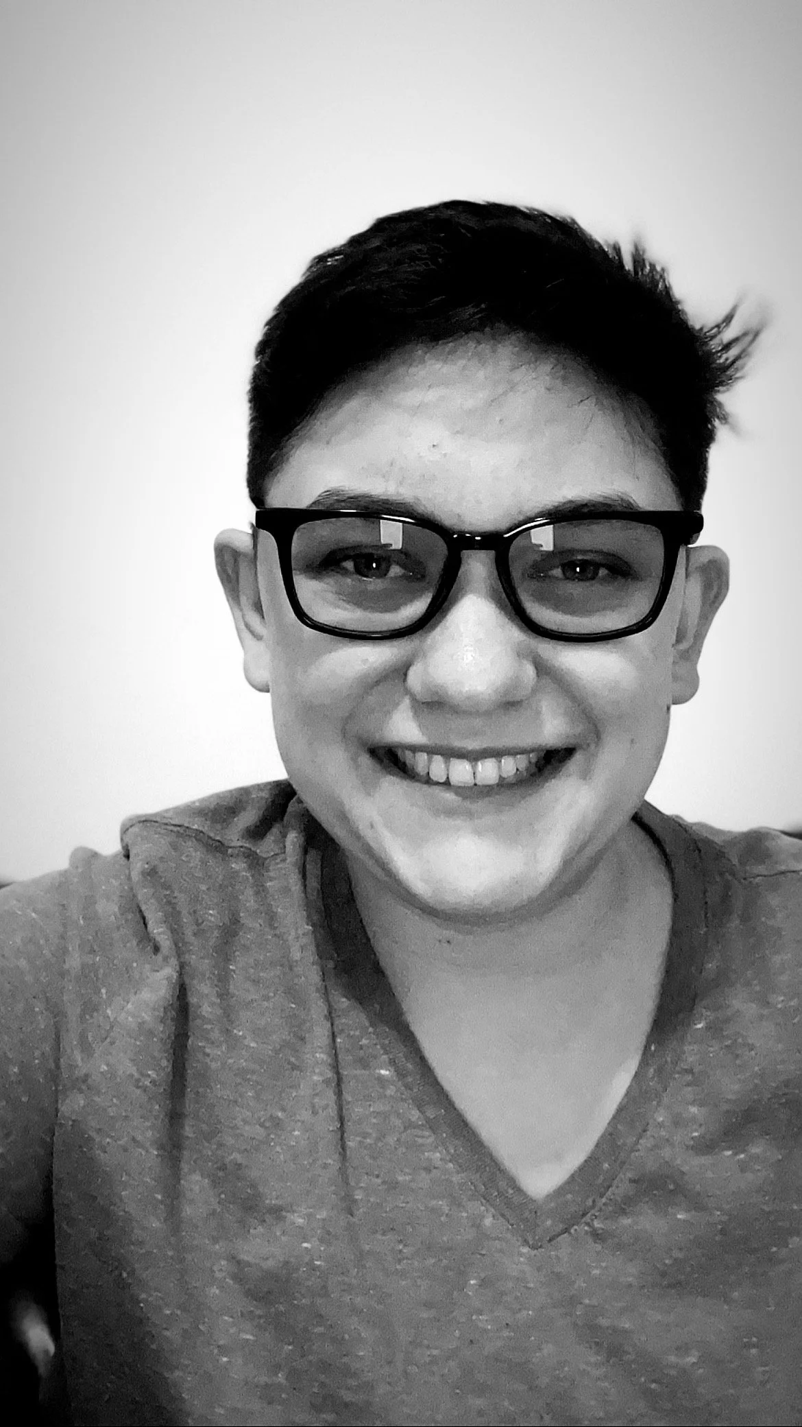 A photo of of Theo in greyscale against a blank wall.