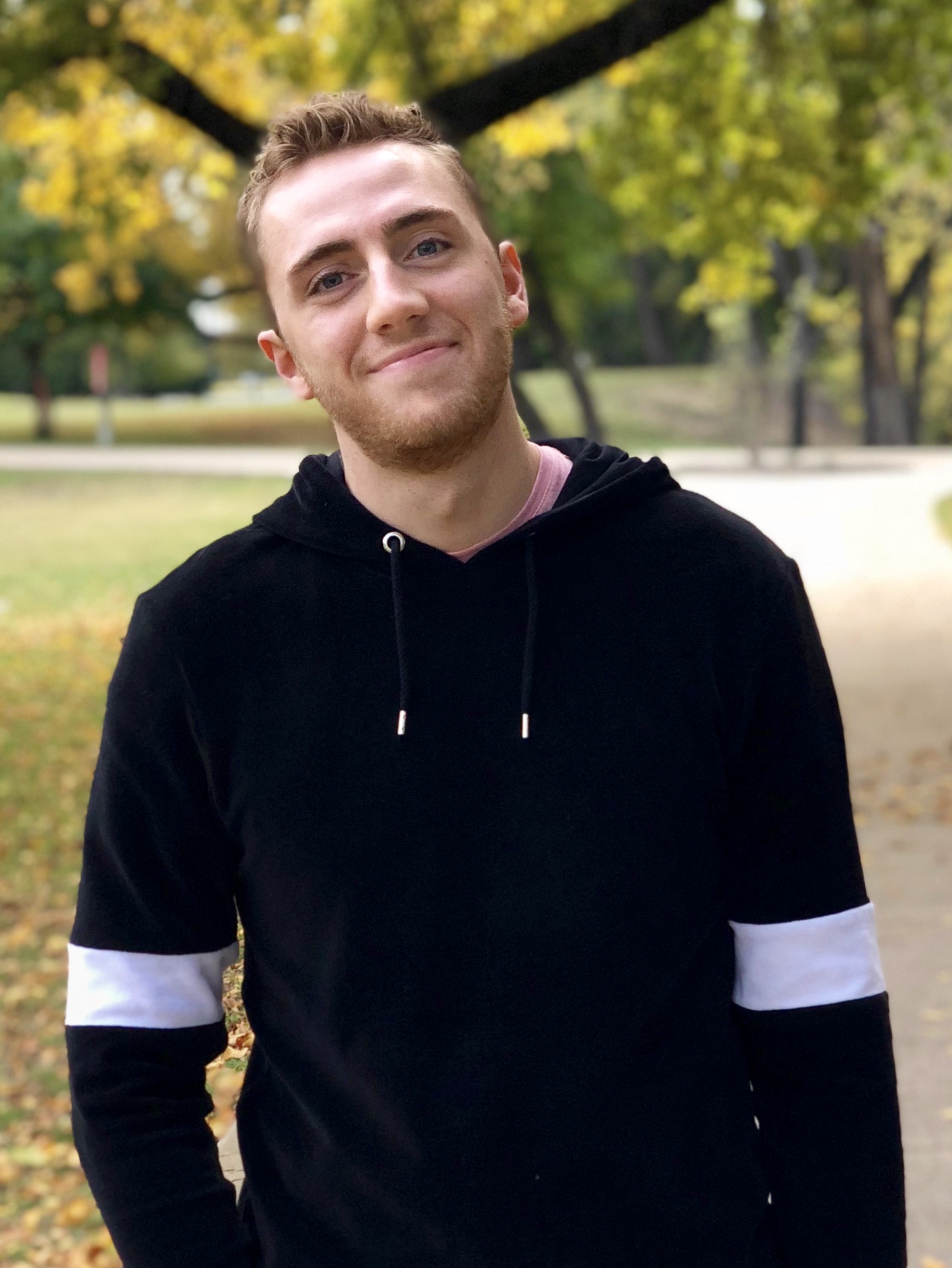 A photo of Weston in a park wearing a sweatshirt.