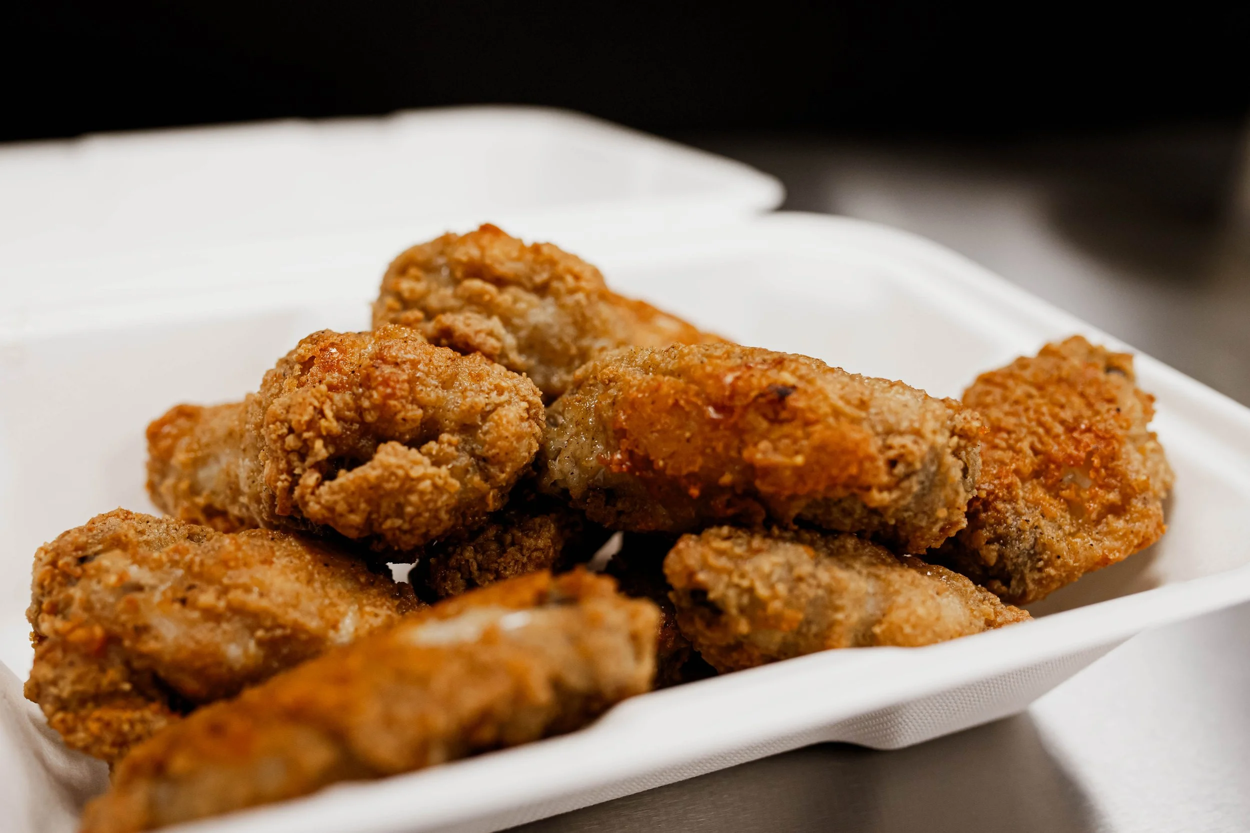 Fried chicken wings in a white take out container