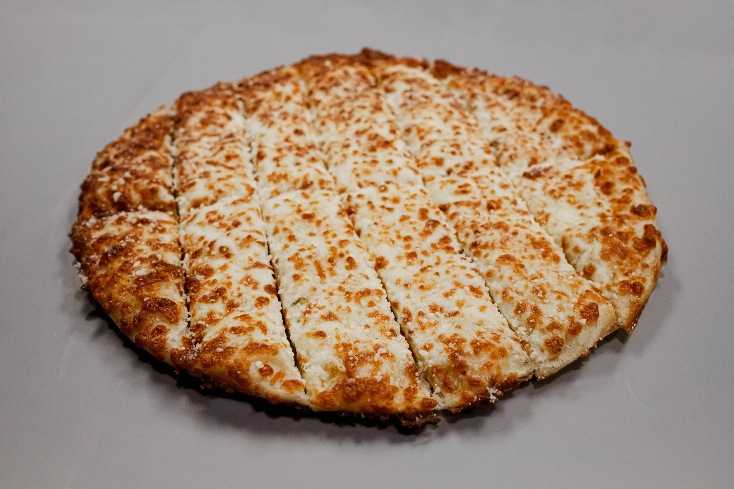 garlic strips with Cheese. with a golden-brown crust, sliced into pieces on a white surface.