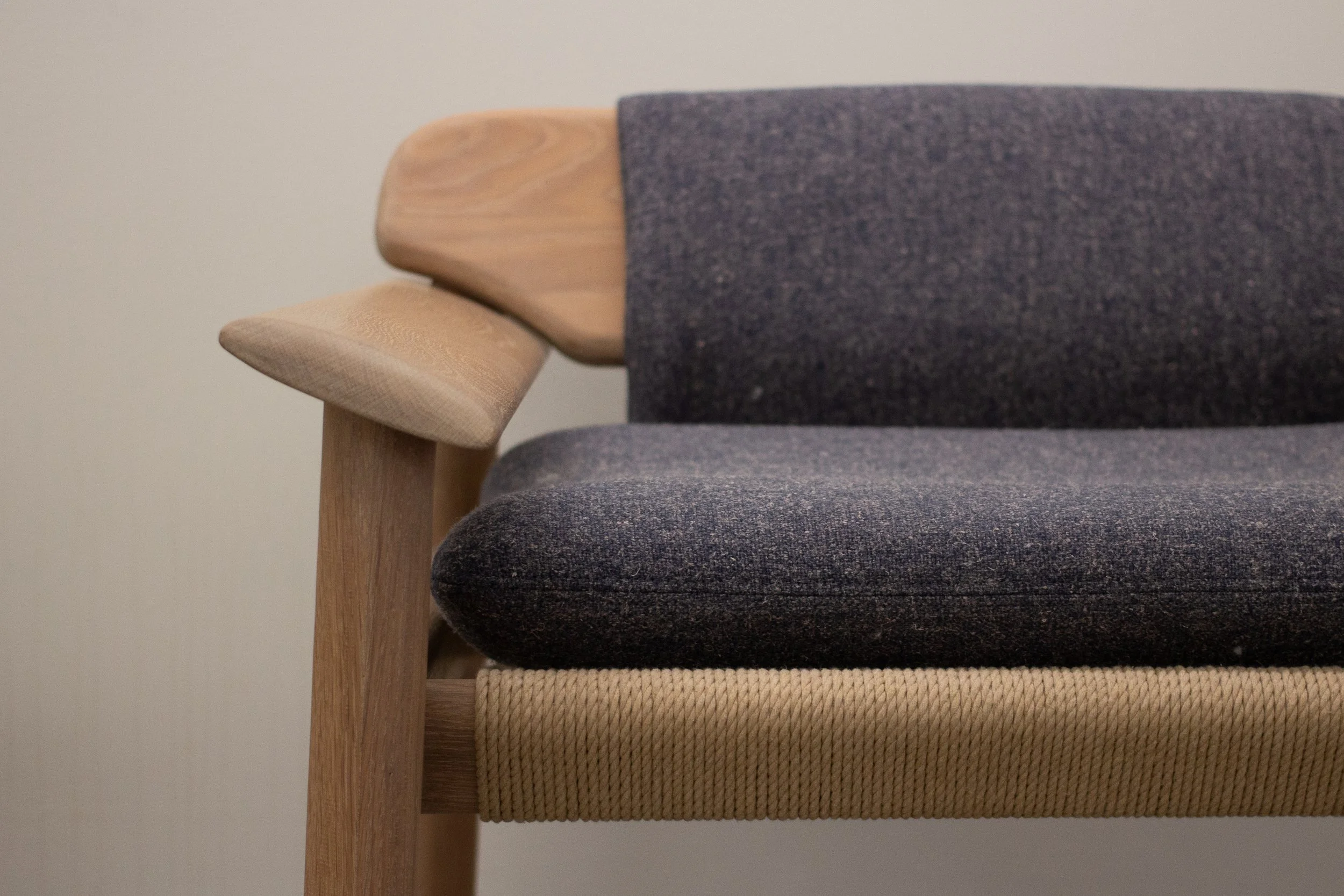 A close-up photo of a modern couch with wooden frame and dark gray fabric upholstery on the seat and backrest.