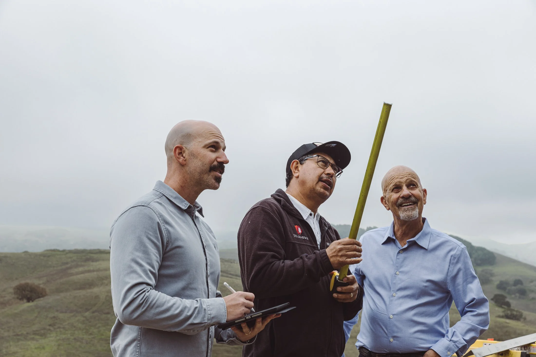 Generational construction team reviewing measurements on residential project