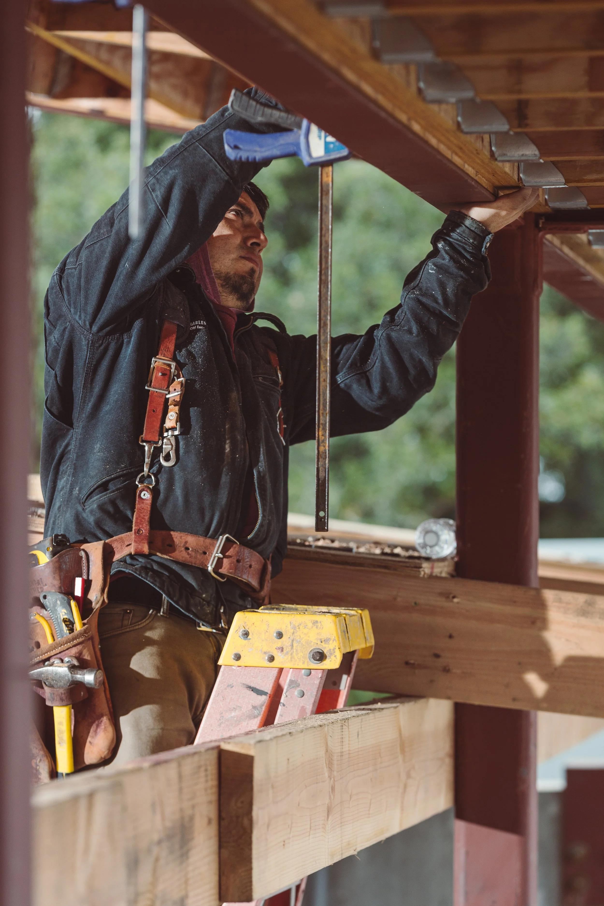 Skilled carpenter installing structural beam during custom home construction