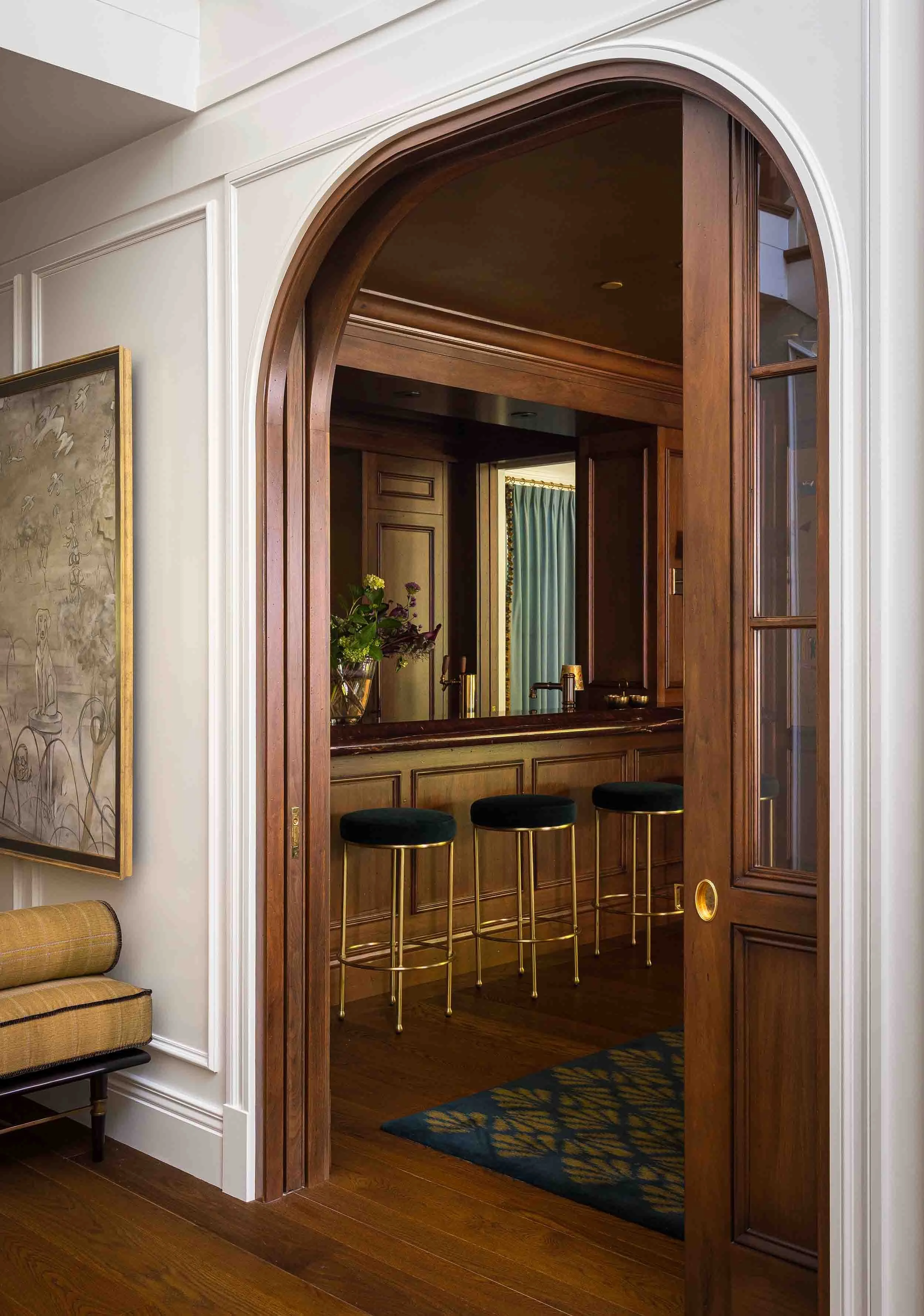 Custom arched walnut doorway with detailed millwork framing the entrance to the bar room in Norman Charles Construction luxury custom home