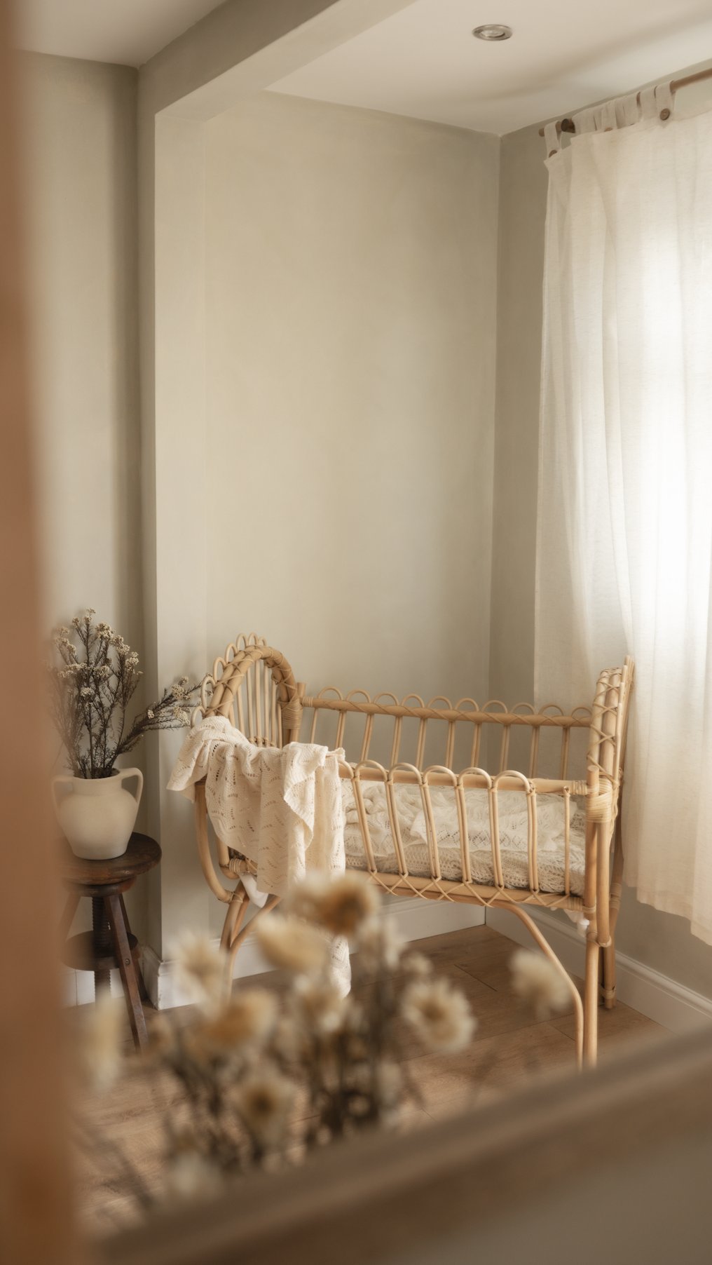 Natural light in Little River Photography's newborn studio, featuring a wicker crib and soft neutral styling.