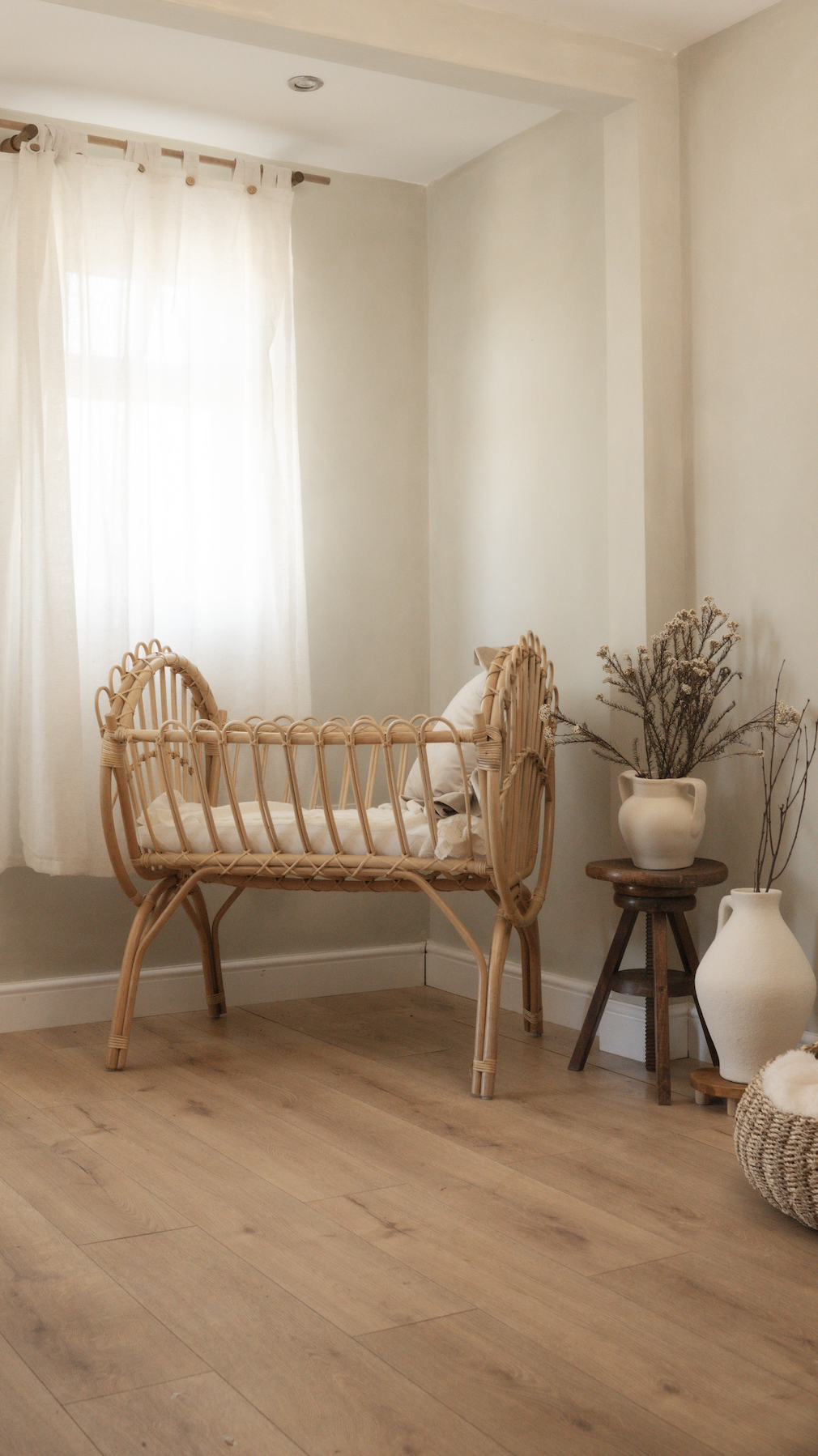 Natural light filling Little River Photography's studio, with a bamboo crib, neutral styling and dried flowers.
