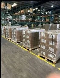 Warehouse with pallets of boxed goods stacked on racks and on the floor.