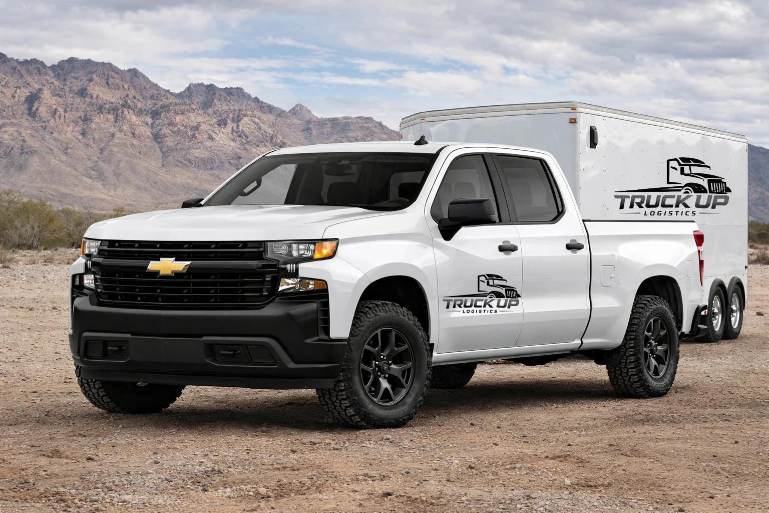 A white Chevrolet pickup truck with a trailer attached, featuring logos for Truck Up Logistics, parked on a dirt road in a desert landscape with mountains in the background.