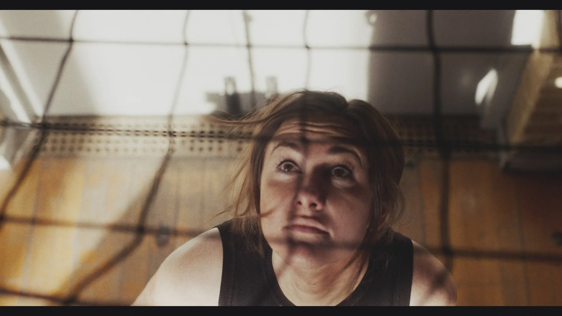 A woman looking upward, viewed through a black net.