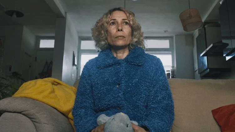 Clear Out – still from a short film produced by Visual Sauce, a woman sits on a couch holding a soft toy.