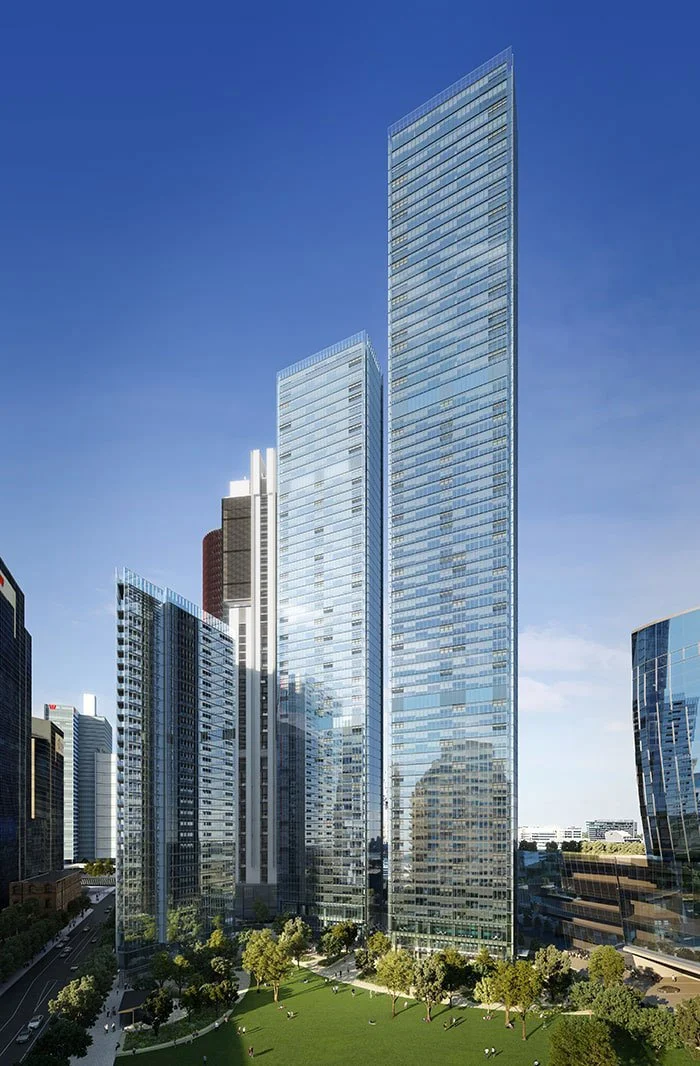 Modern glass skyscrapers in a downtown city with greenery and a blue sky.