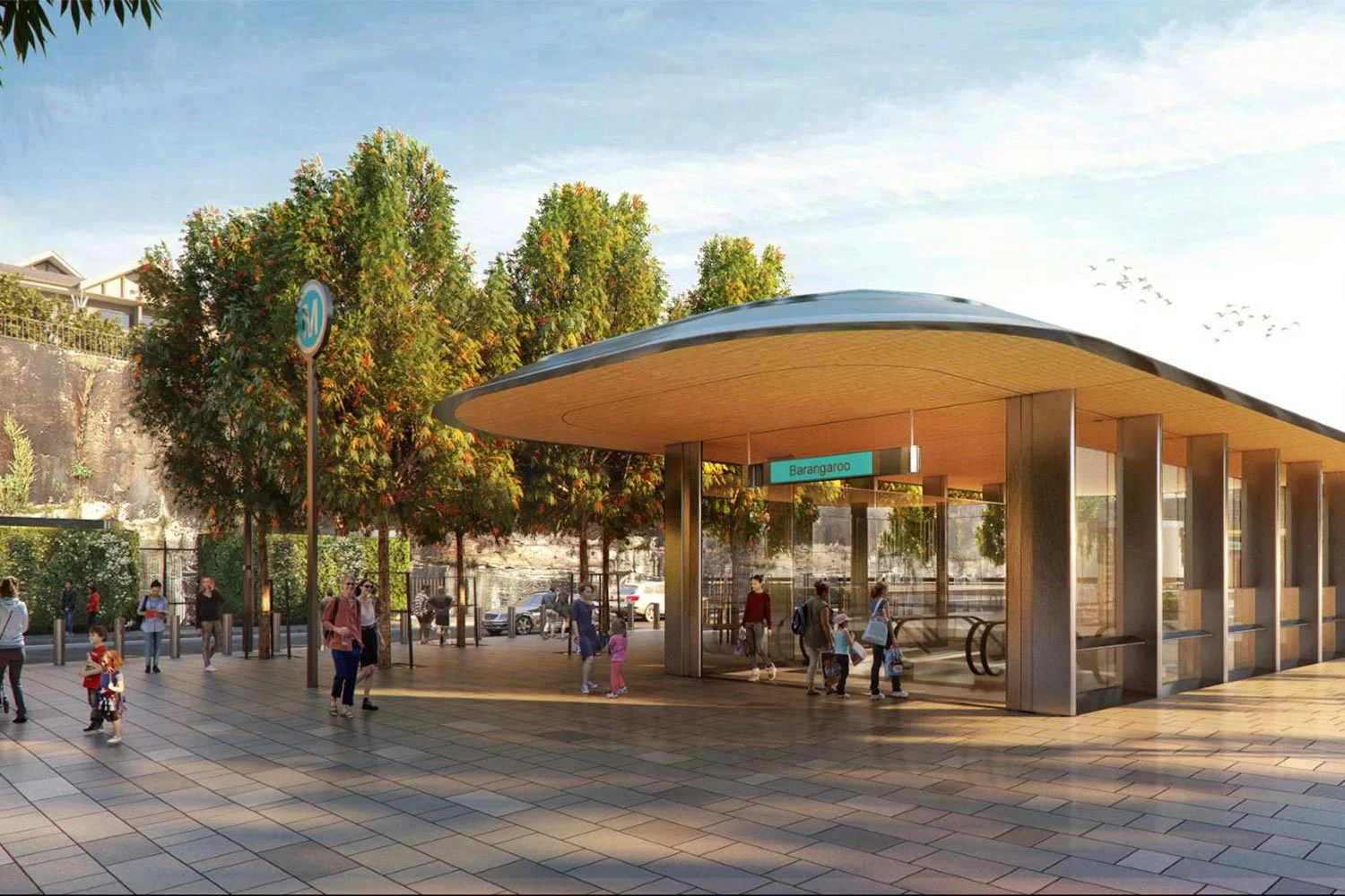 People waiting at a modern subway station entrance with trees and parked cars in the background.