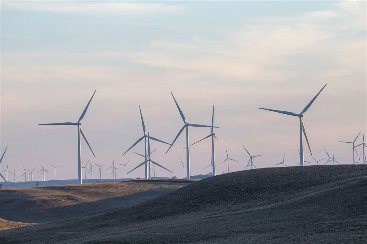 A landscape with multiple wind turbines on rolling hills under a cloudy sky.