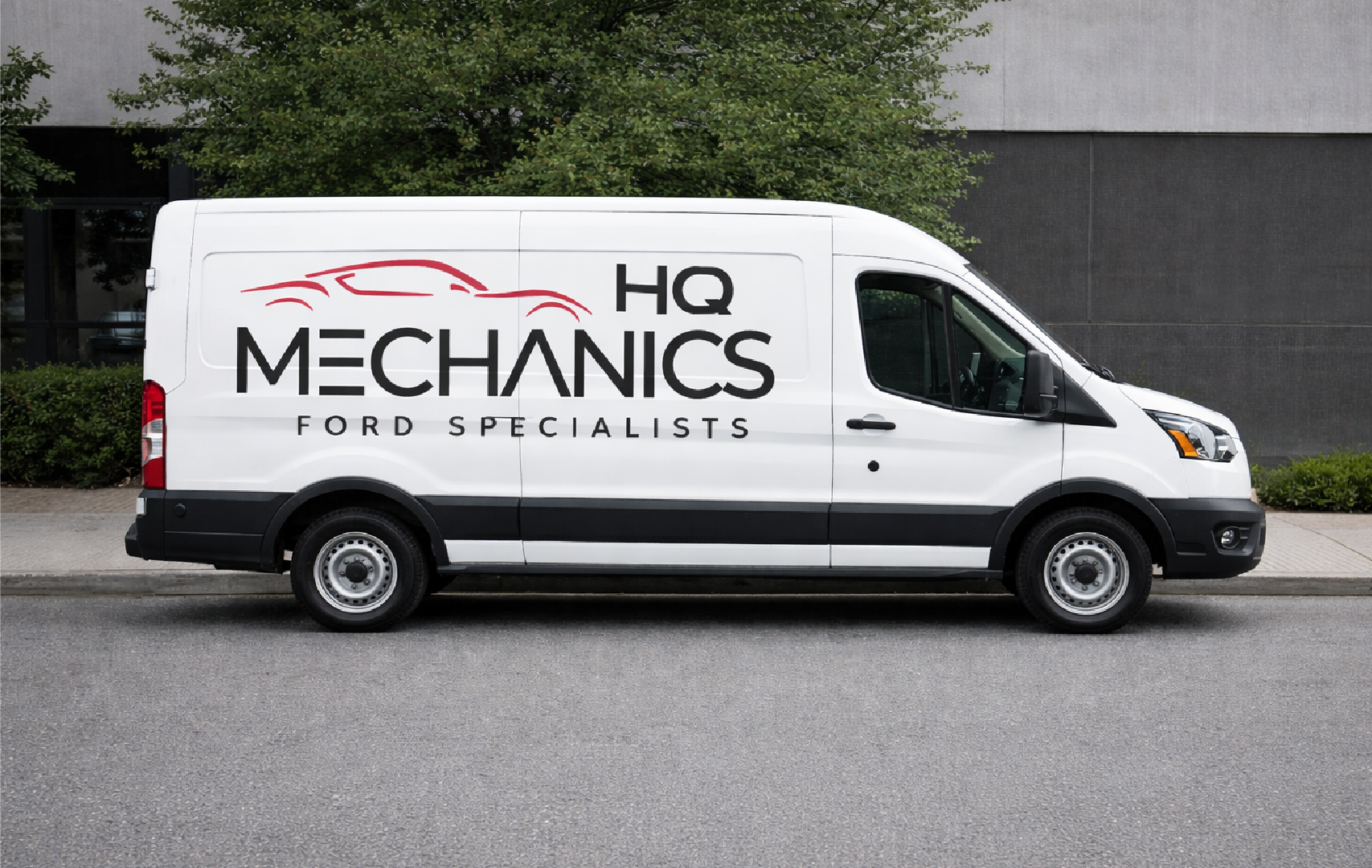 A white service van parked on a city street with the logo 'HQ Mechanics Ford Specialists' and a red outline of a car on the side.