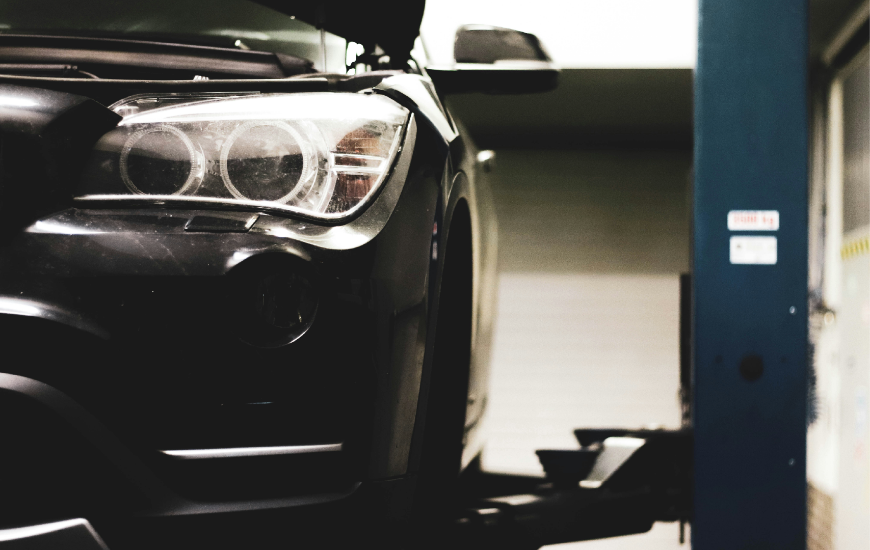 A black car on a hydraulic lift inside a garage or auto shop.