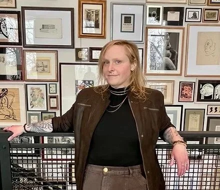 Photo of Bailey standing in front of gallery wall
