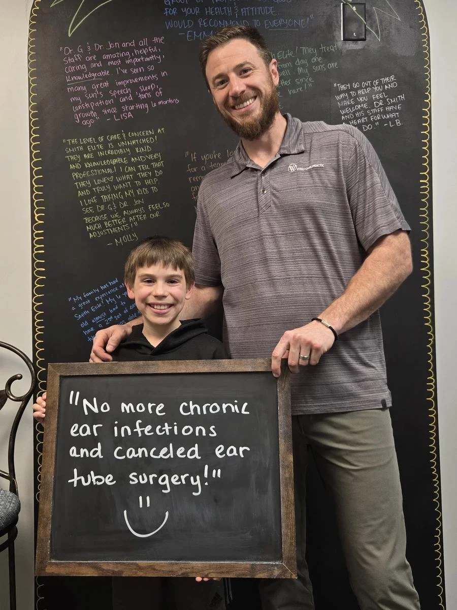 Dad holding chalkboard about cancelled ear tube surgery after chiropractic treatment in Liberty MO