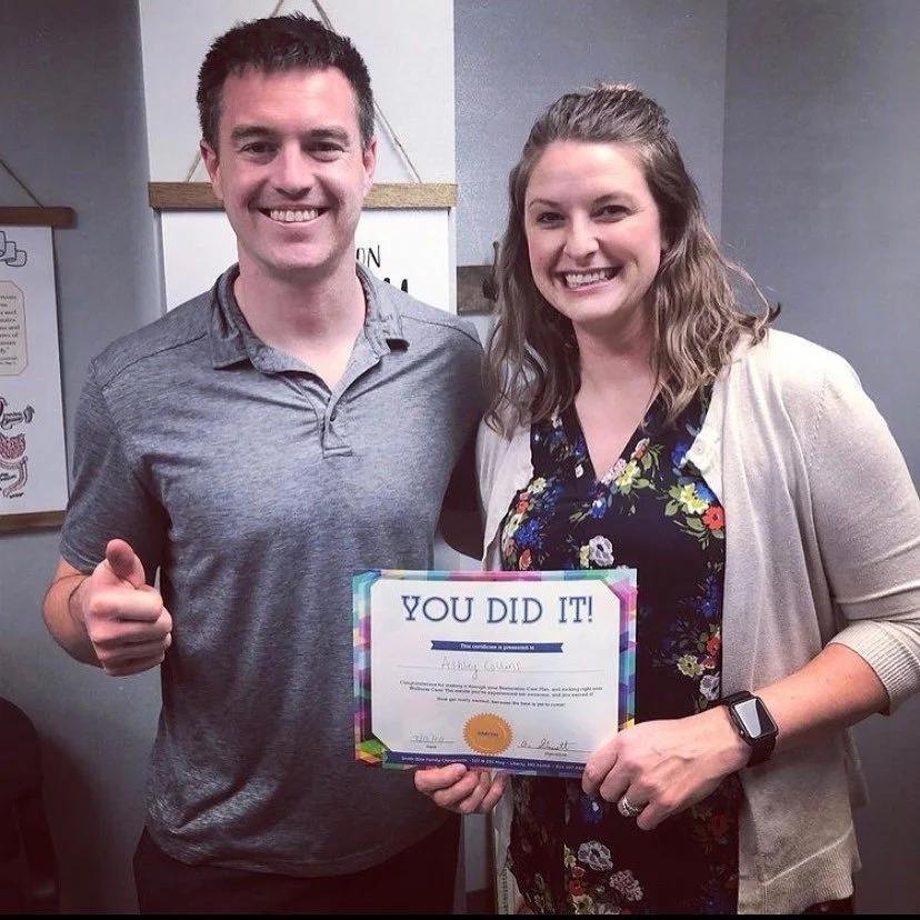 Dr and woman patient holding care completion certificate after back pain treatment