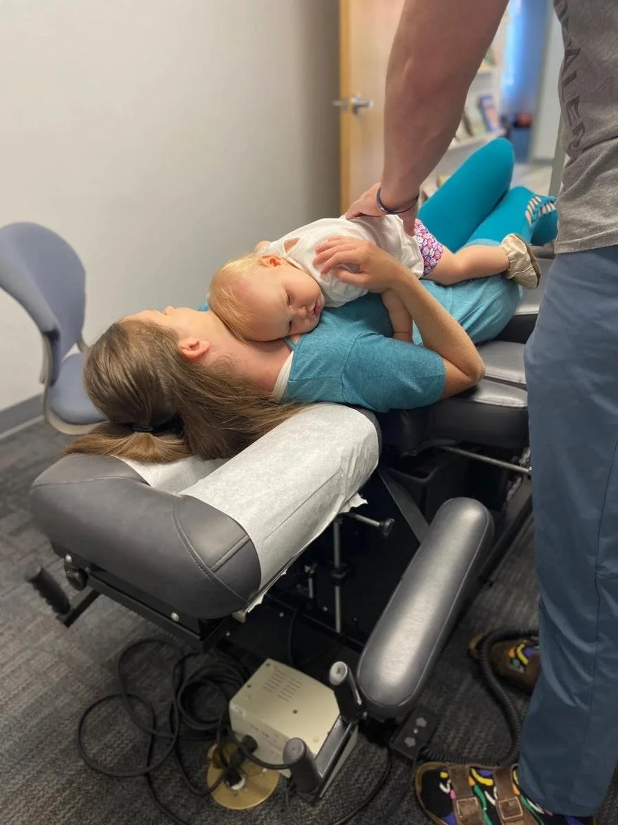 Newborn receiving gentle spinal assessment during infant chiropractic visit in Liberty MO