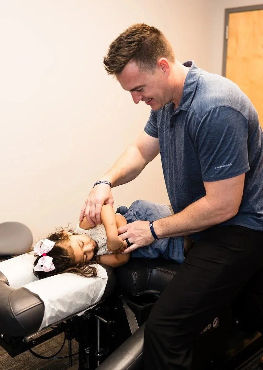 Girl smiling during gentle chiropractic adjustment for kids