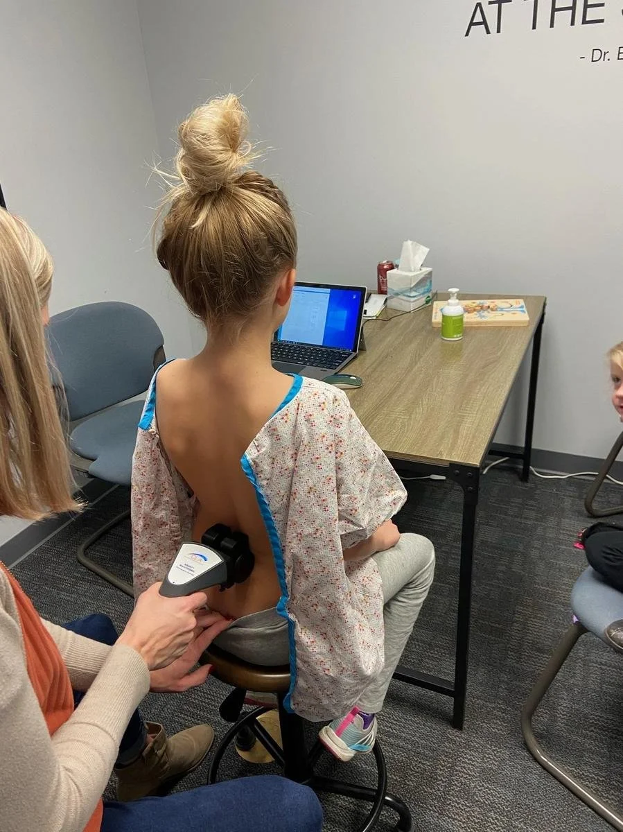 Chiropractor adjusting young child while parent watches