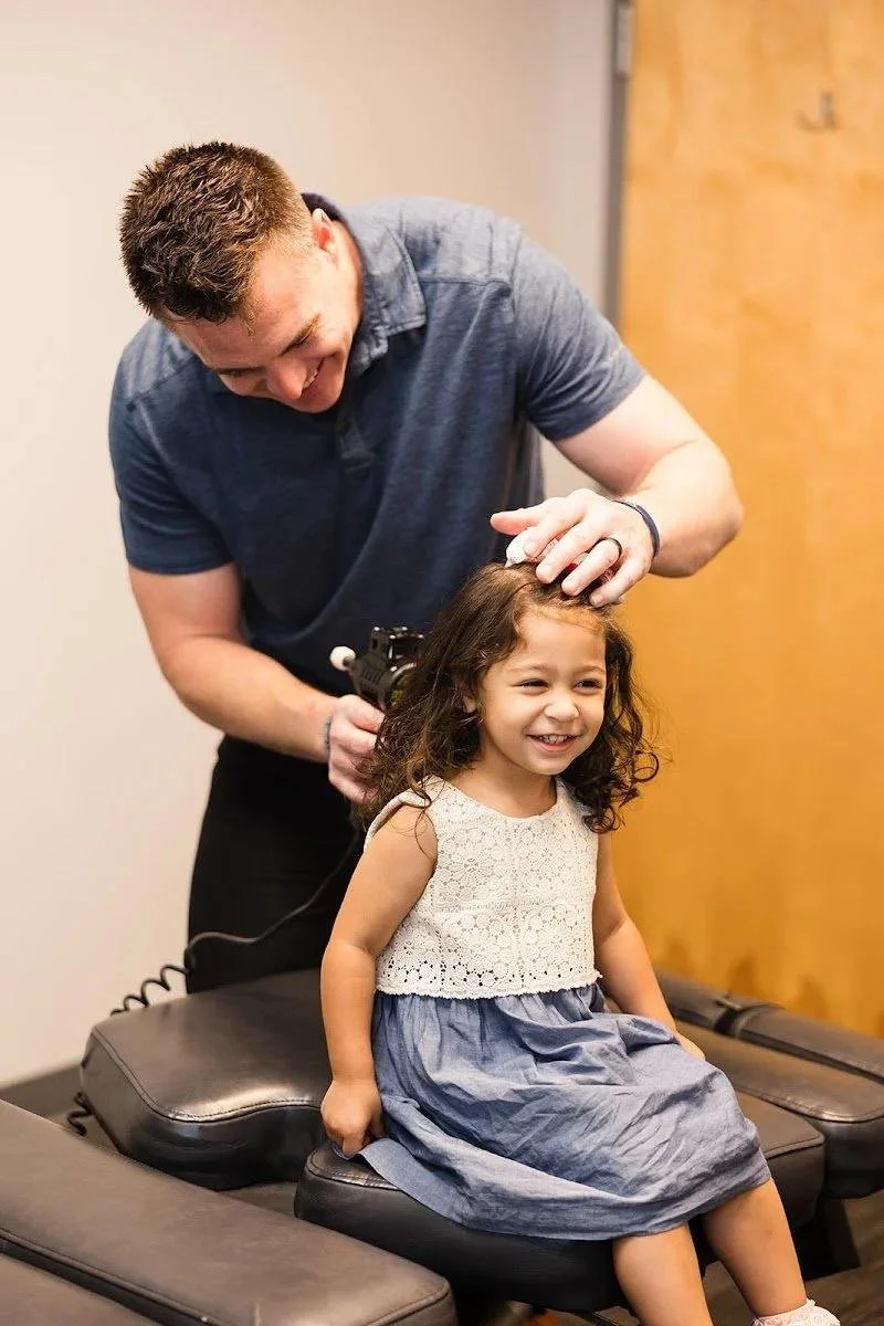 Dr Garrett Smith adjusting young girl during ADHD focus chiropractic treatment in Liberty MO