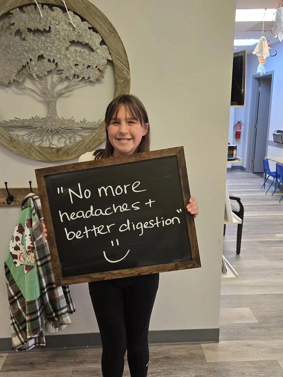Kid holding chalkboard about no more headaches and better digestion after chiropractic care in Liberty MO