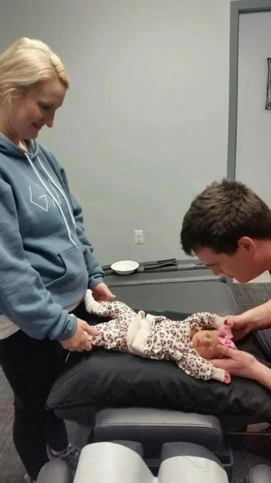 Newborn gently cradled during chiropractic colic treatment