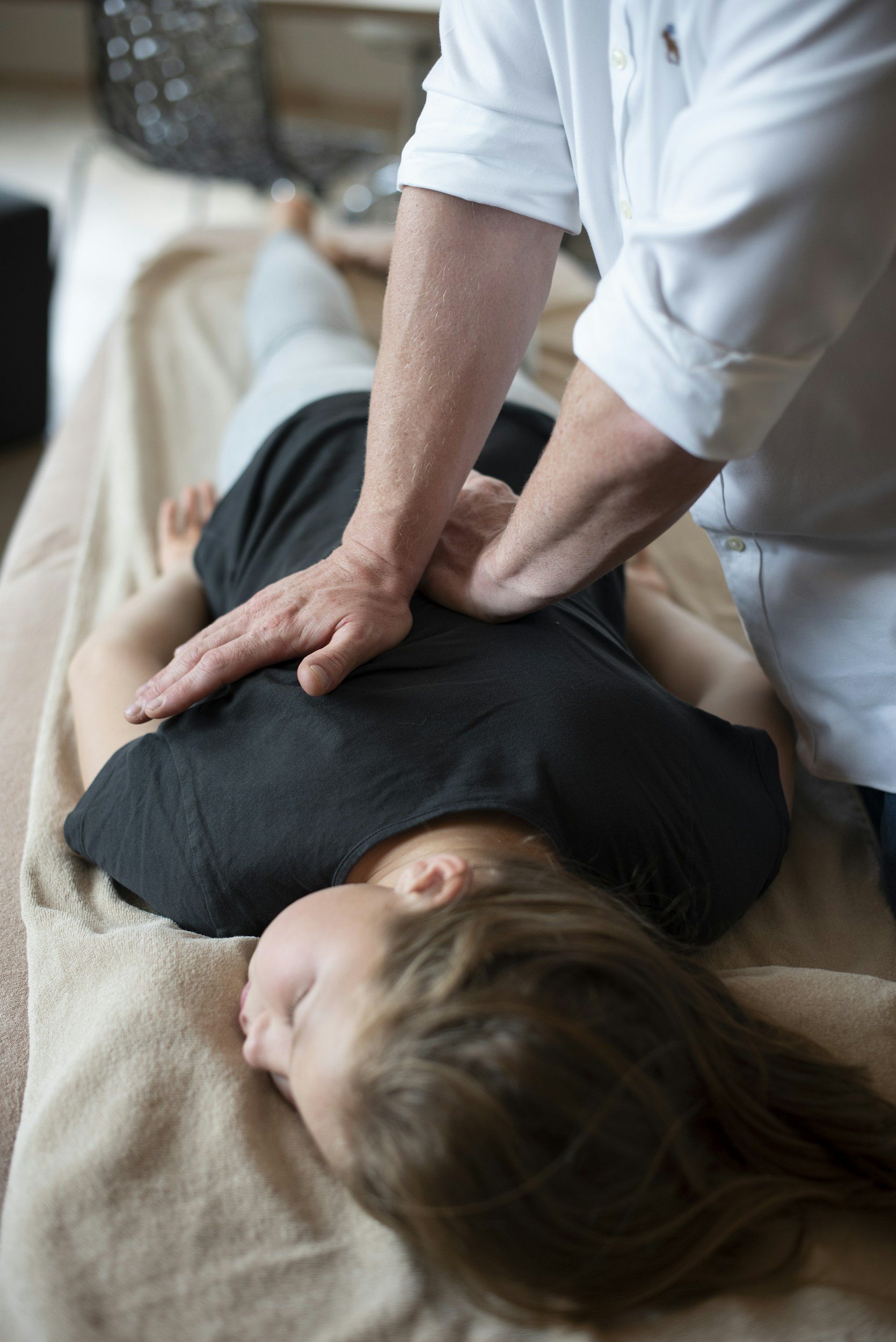 Chiropractor performing spinal adjustment on a patient lying face down on a treatment table.