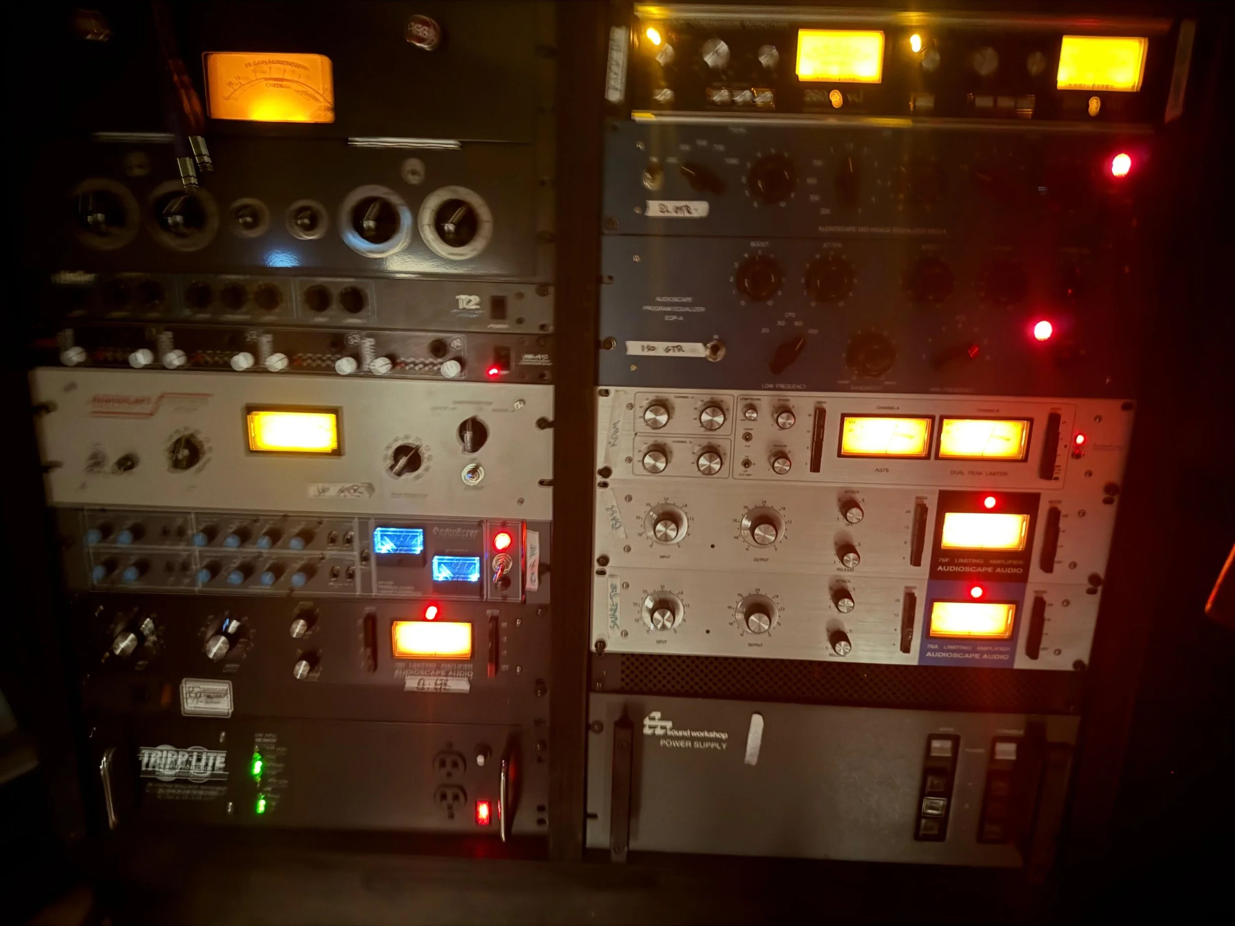 A rack of audio equipment with various meters, knobs, switches, and illuminated display screens, used for sound mixing and audio processing.