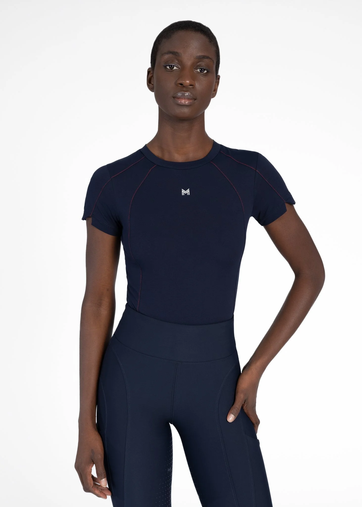 A woman wearing a navy blue athletic shirt and leggings, standing against a plain white background.