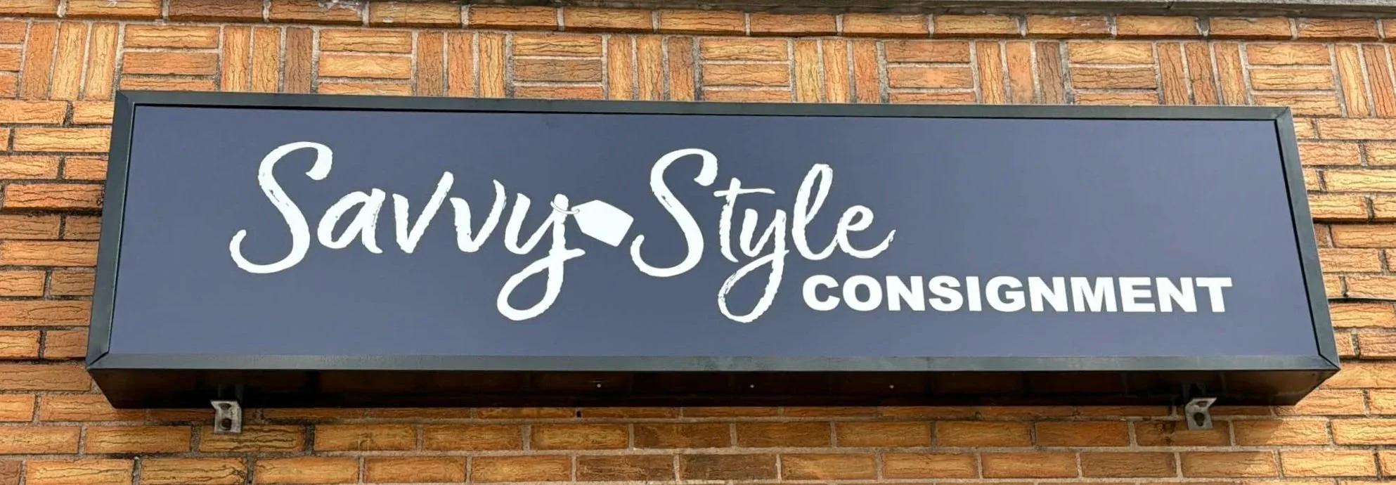 Store sign reading "Savvy Style Consignment" mounted on a brick wall.
