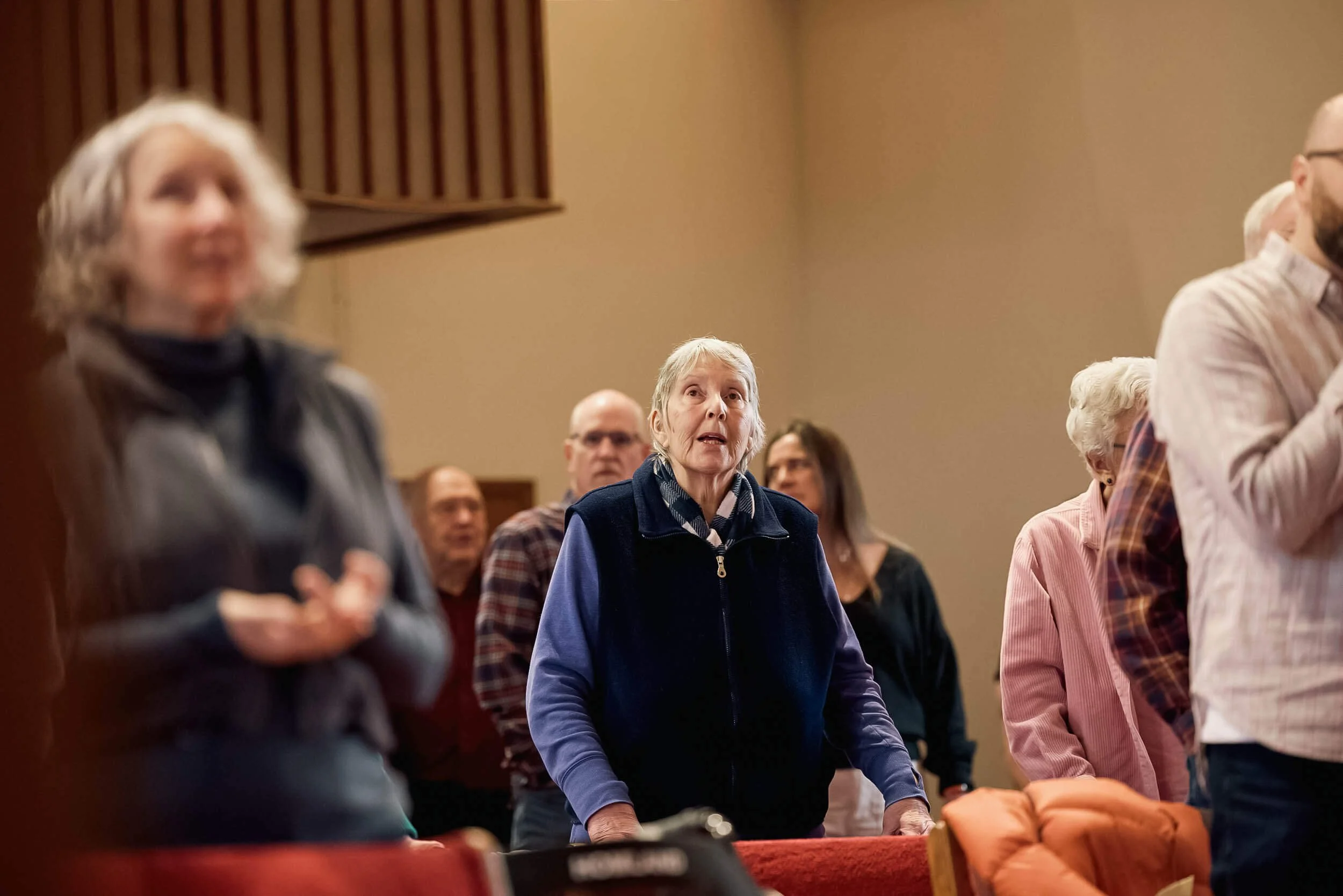 An older woman stands and sings during worship, surrounded by fellow congregation members at Crown Hill Church in Seattle's Crown Hill neighborhood.