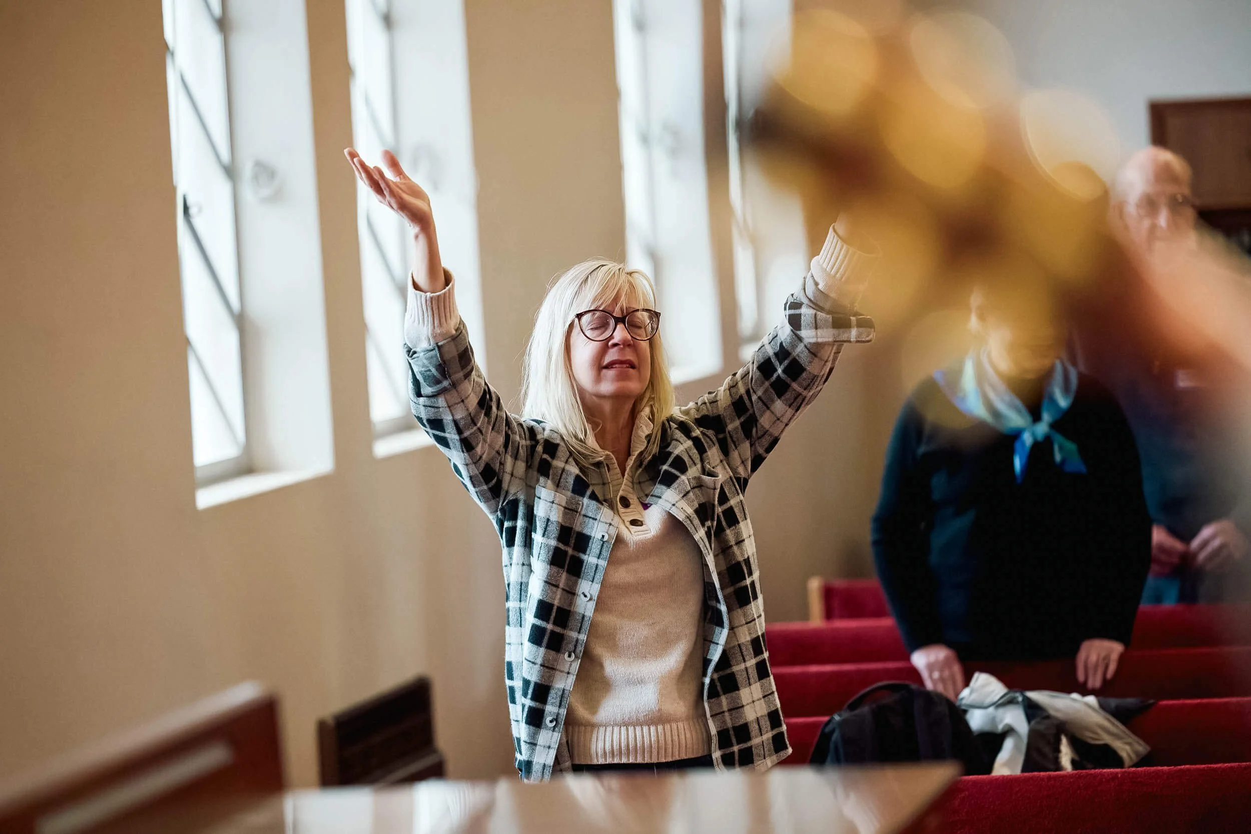 A woman with closed eyes and raised hands worships during a Sunday service at Crown Hill Church.
