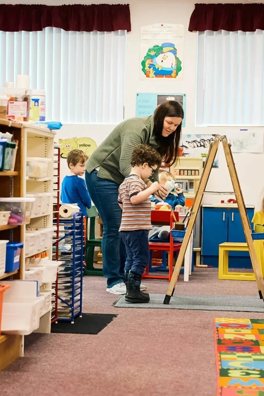 Children and teachers painting with an easel.
