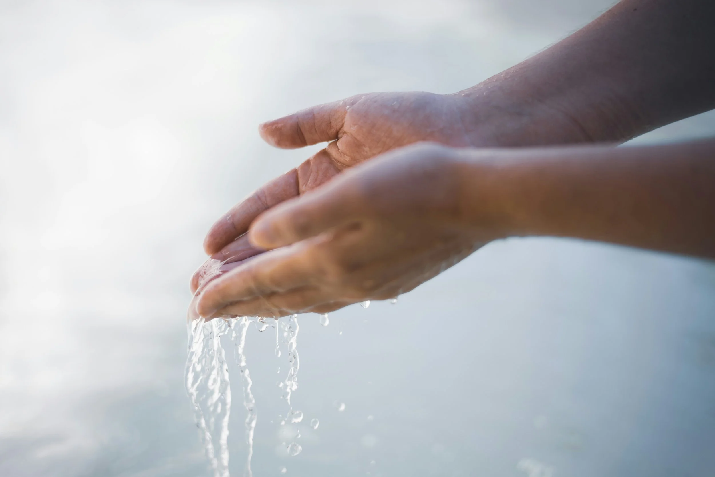 Two hands cupped together with water flowing through them, representing the spirit of generous giving at Crown Hill Church.