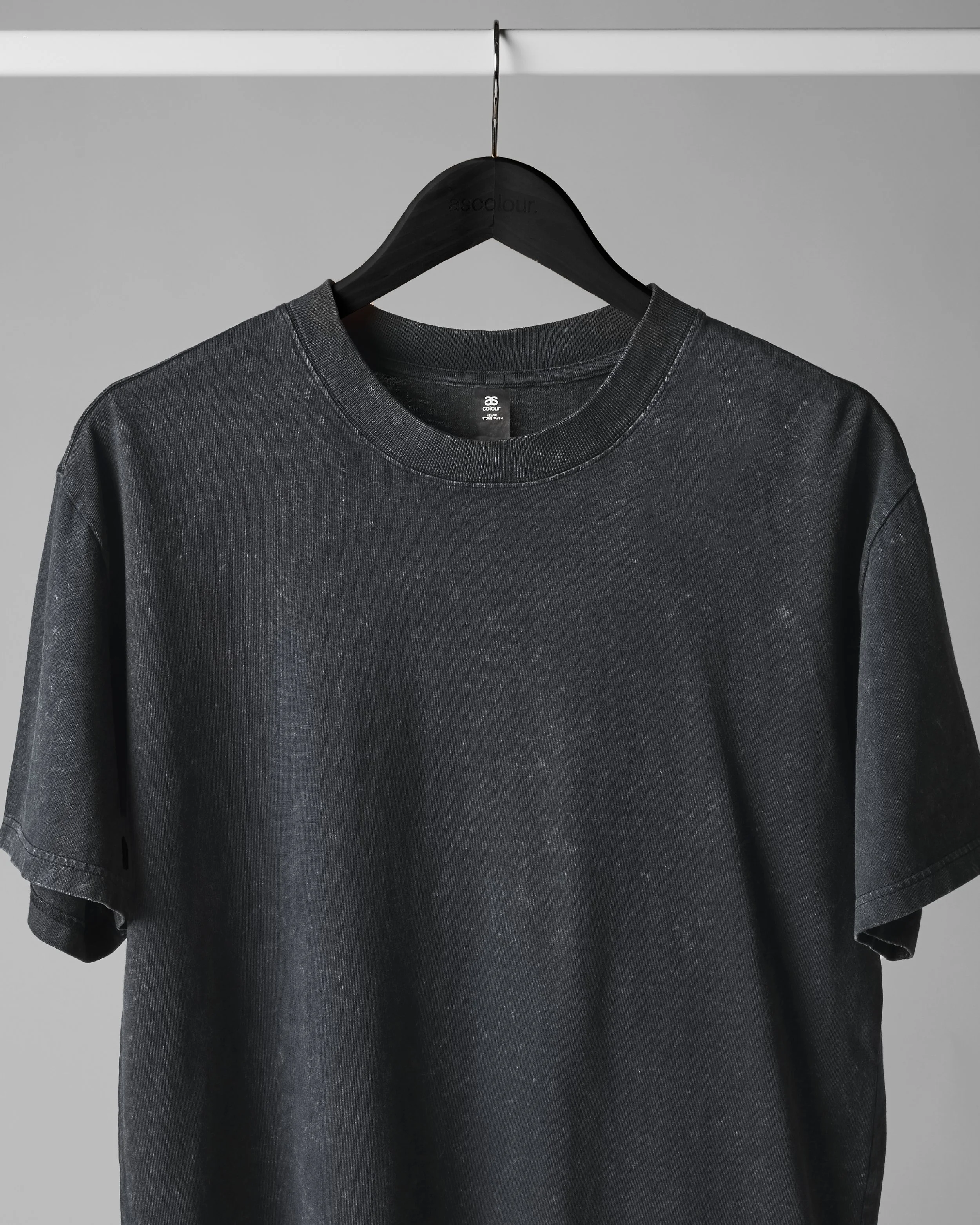 A black sweatshirt hanging on a black hanger against a plain gray background.